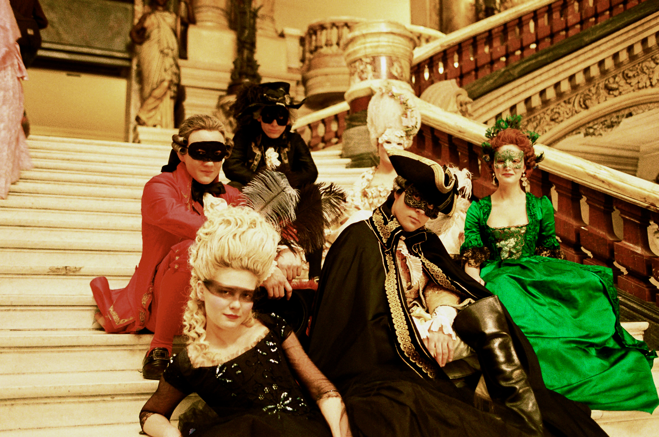 Still from the movie Marie Antoinette showing the cast lounging on palace steps at a costume ball