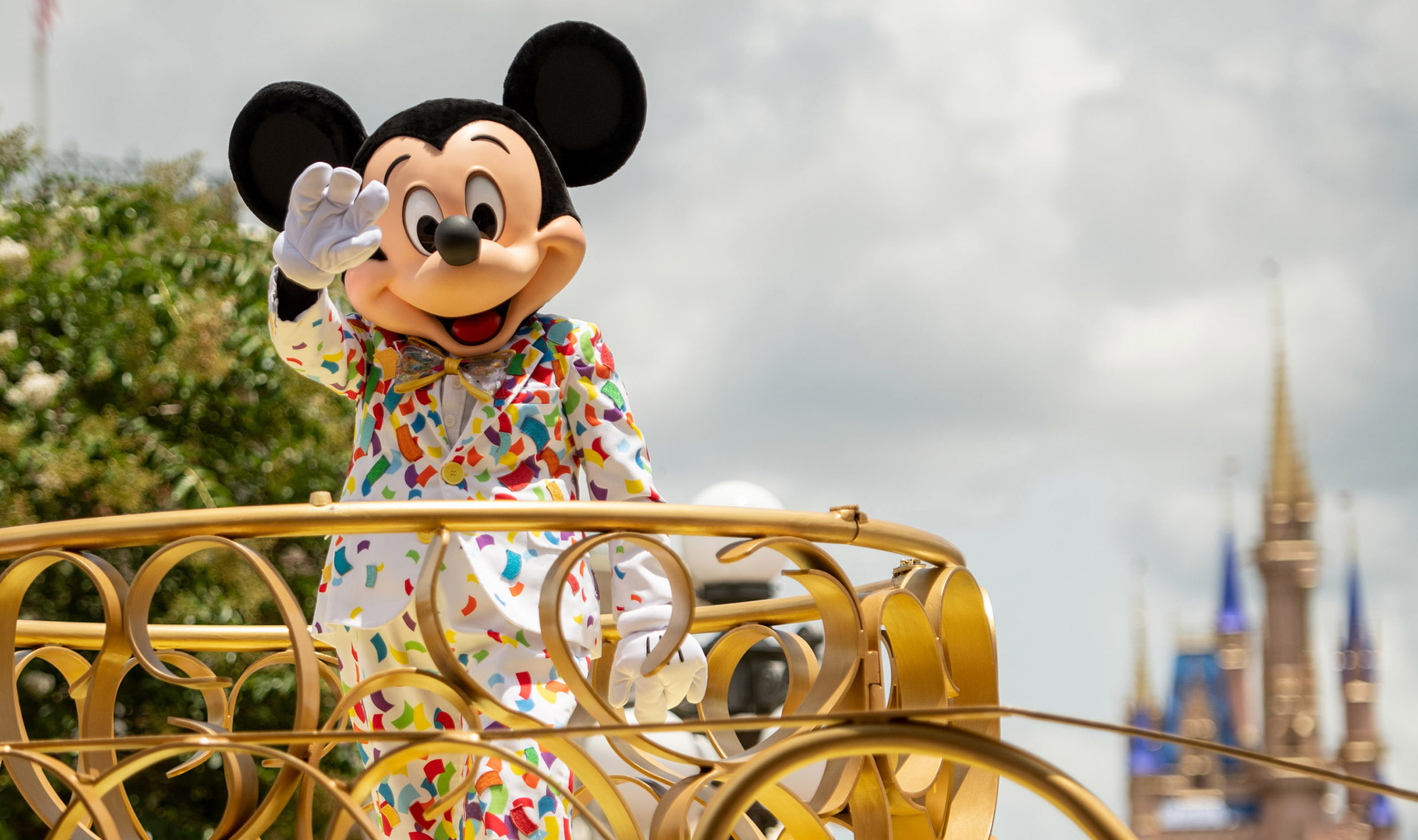 Performer dressed as Mickey Mouse stands on a parade float at Disney World