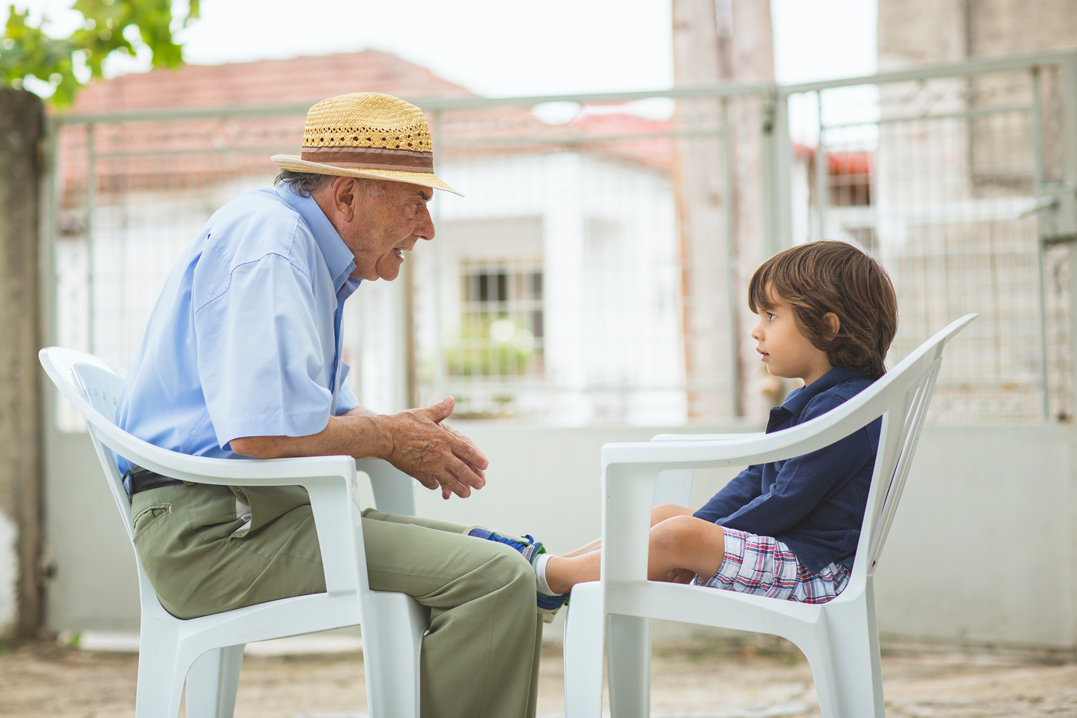 Portrait of a small boy with his grandfather sitting across from each other outside
