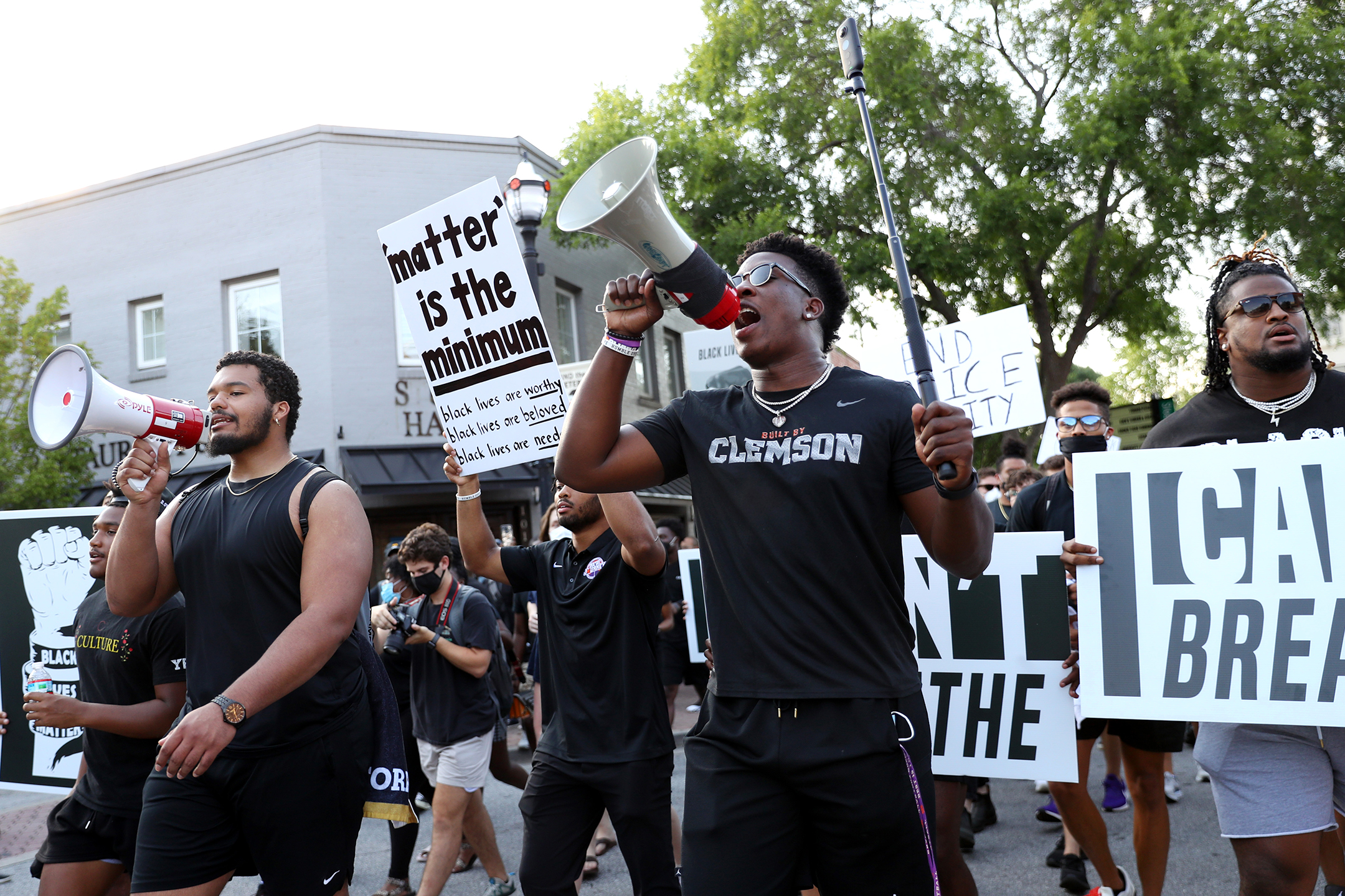 Young black men march in protest with their fists raised and carrying signs