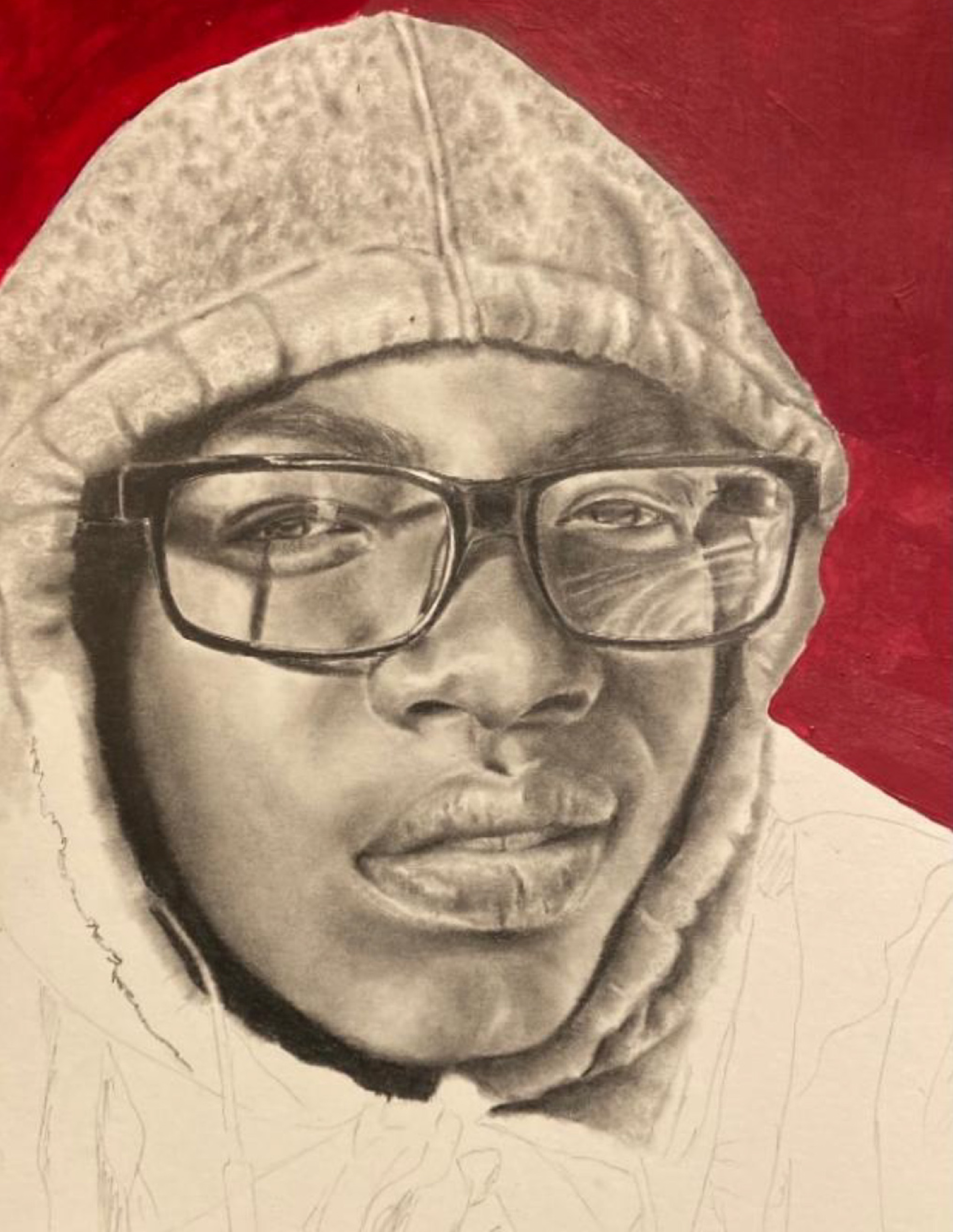 Black and white portrait of a young black man wearing glasses in a hoodie against a red background