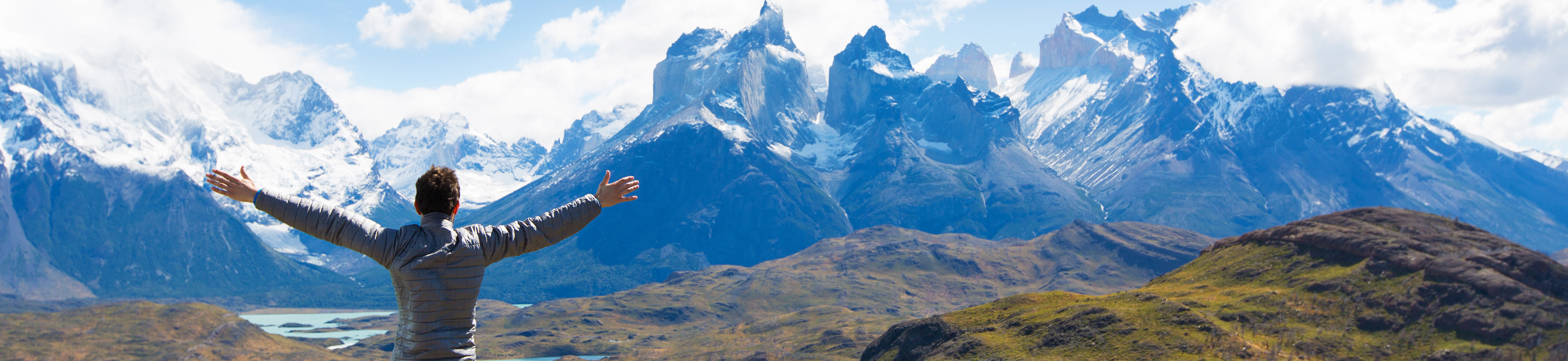 man with arms raised looking at a mountain range in patagonia, chile