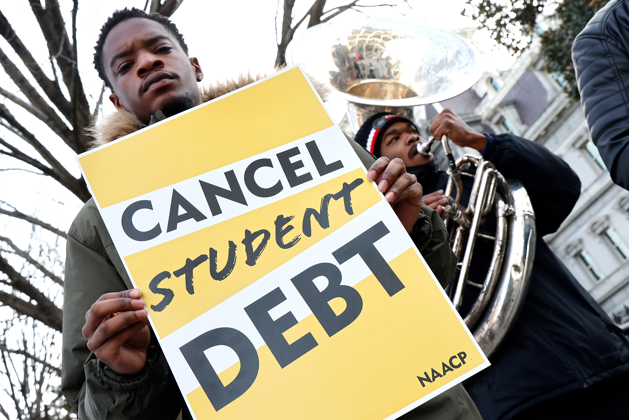 Young man holding a sign that reads Cancel Student Debt