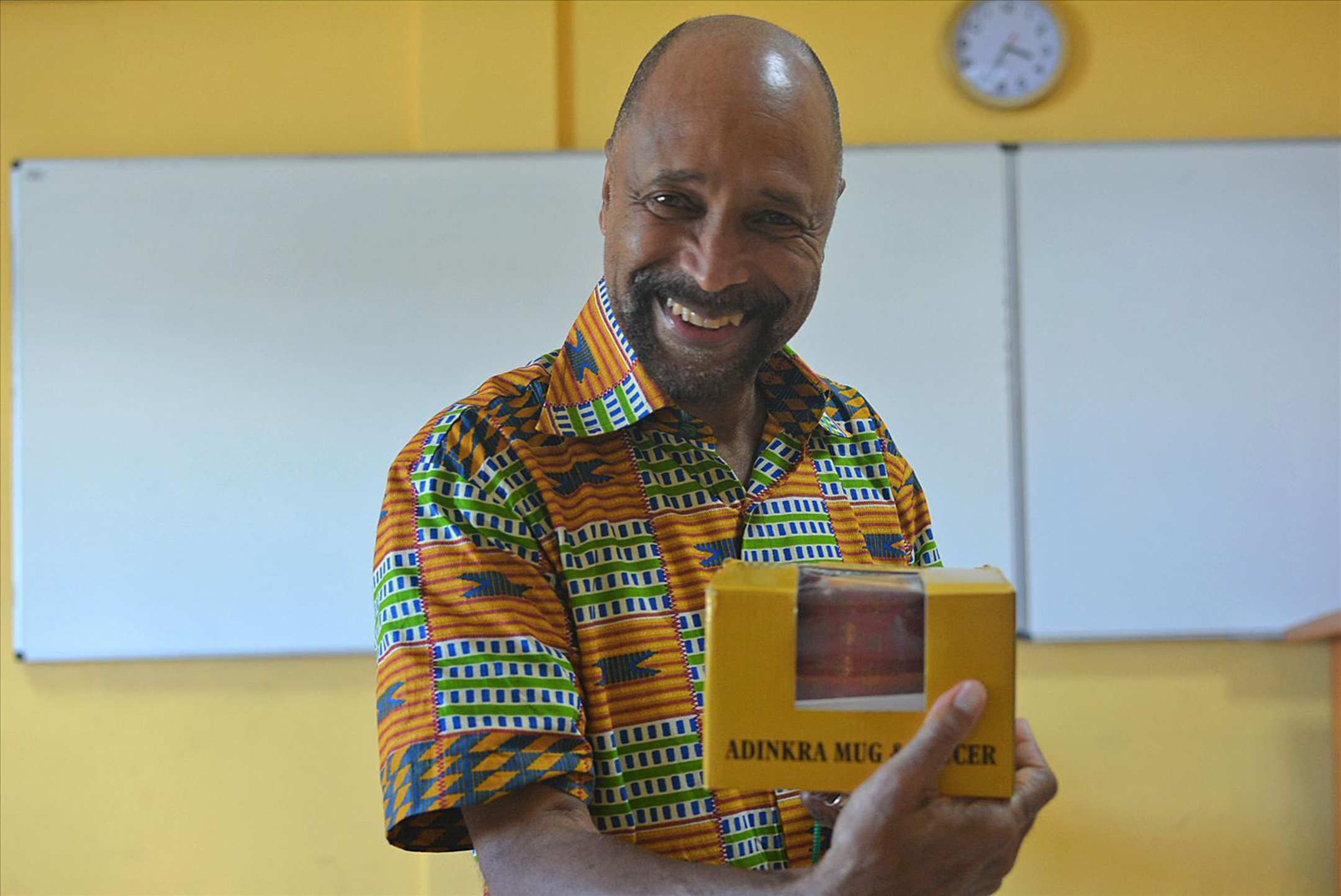 Photo of Clarence Skip Ellis smiling while holding a small yellow box