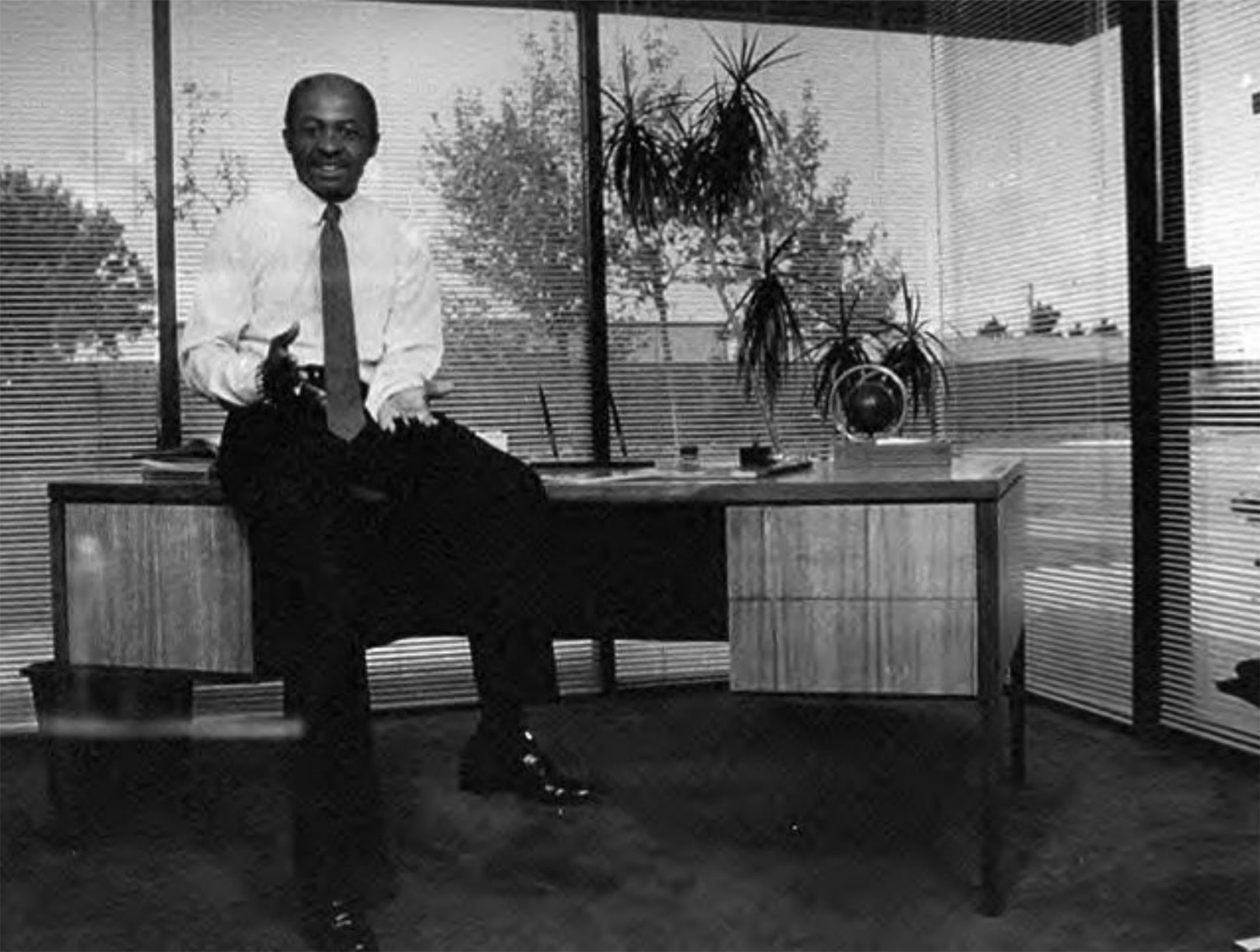 Black and white photo of a man sitting on his desk