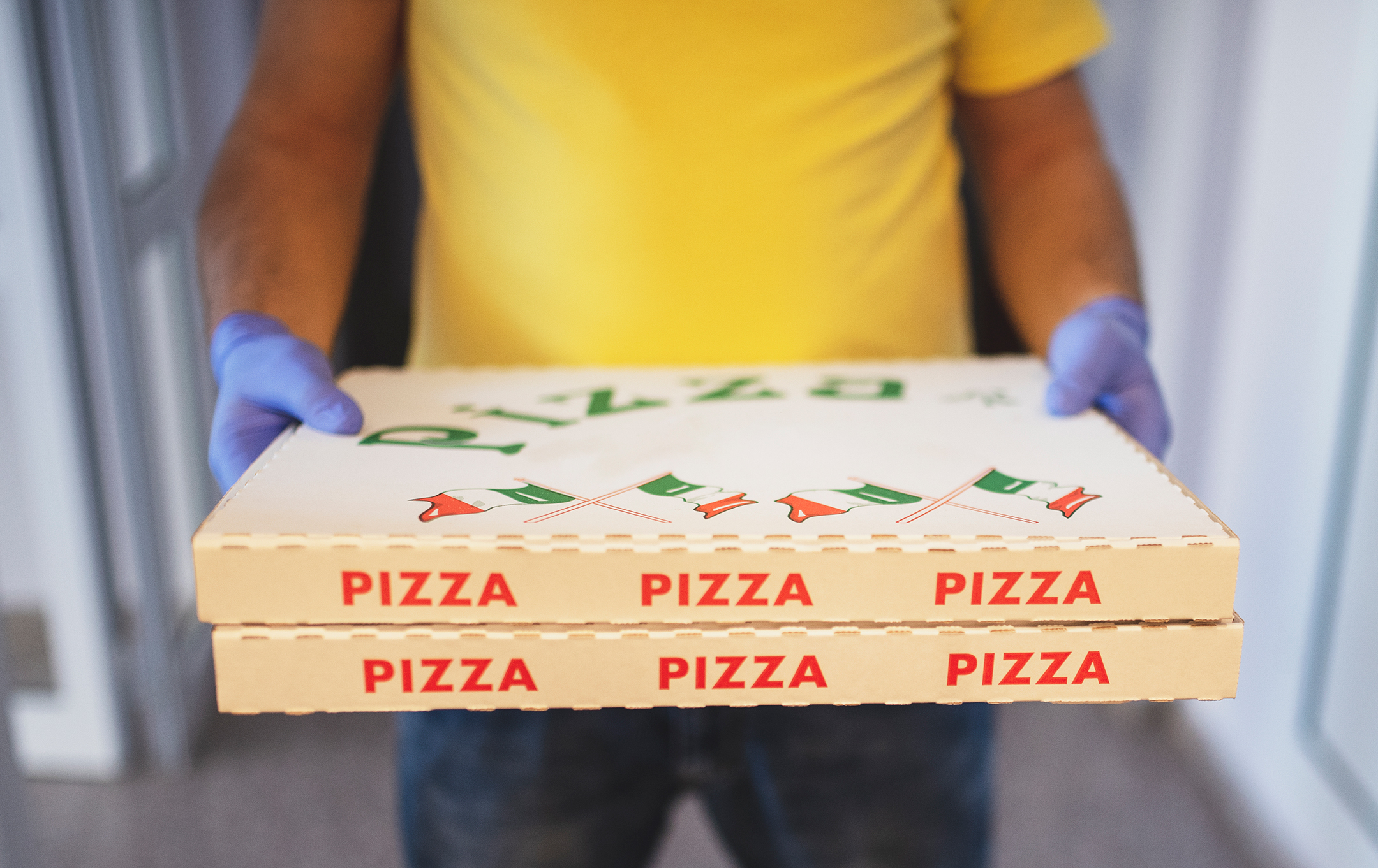 a man with safety gloves and face mask delivers pizza