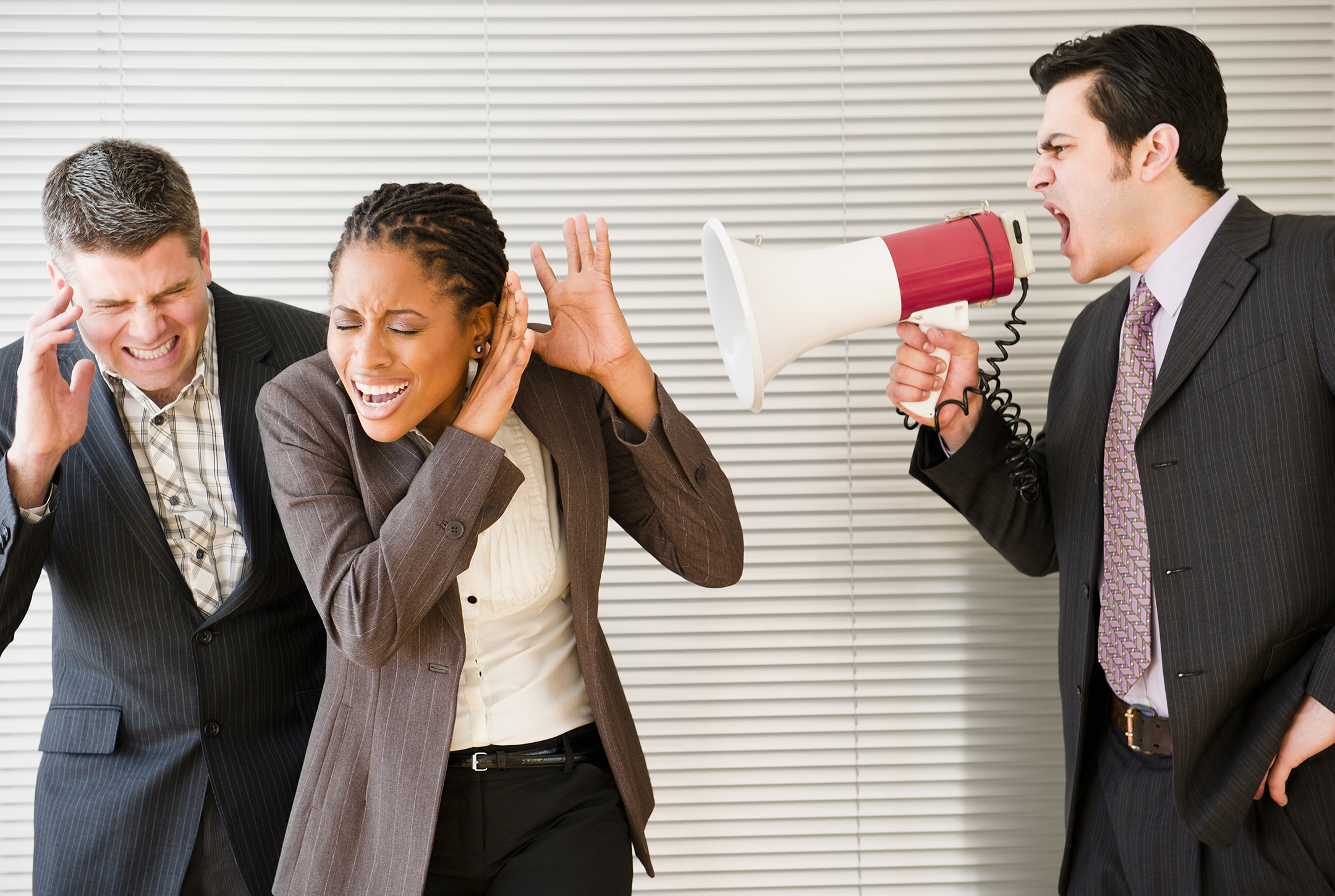 Businessman shouting through bullhorn at co-workers