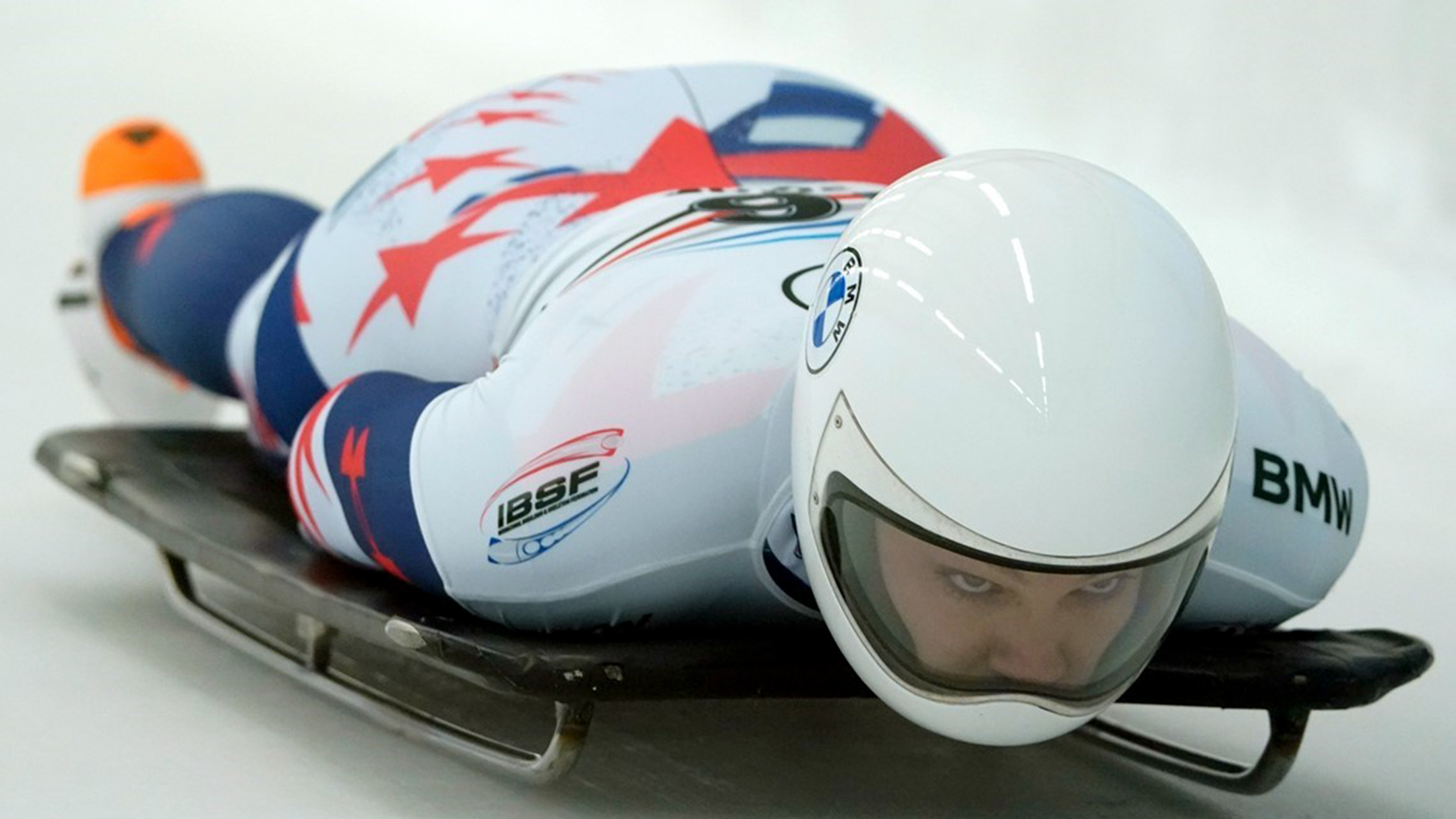 Close up of American skeleton athlete laying flat on her board
