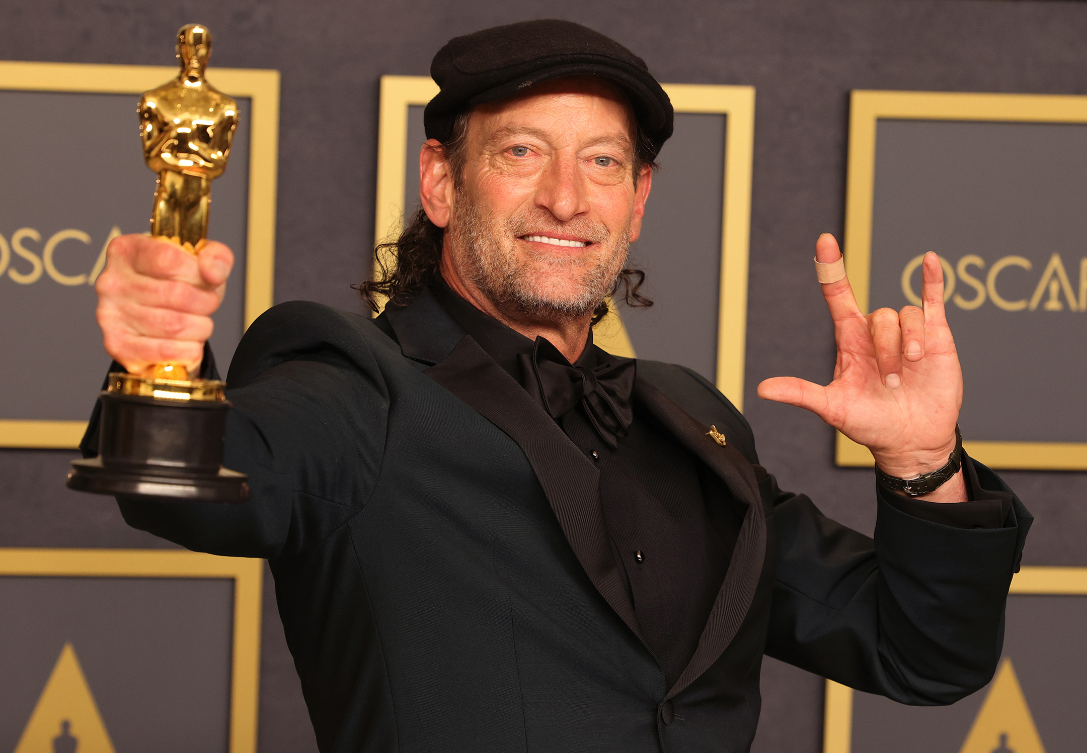 Man holding an academy award trophy poses for the camera