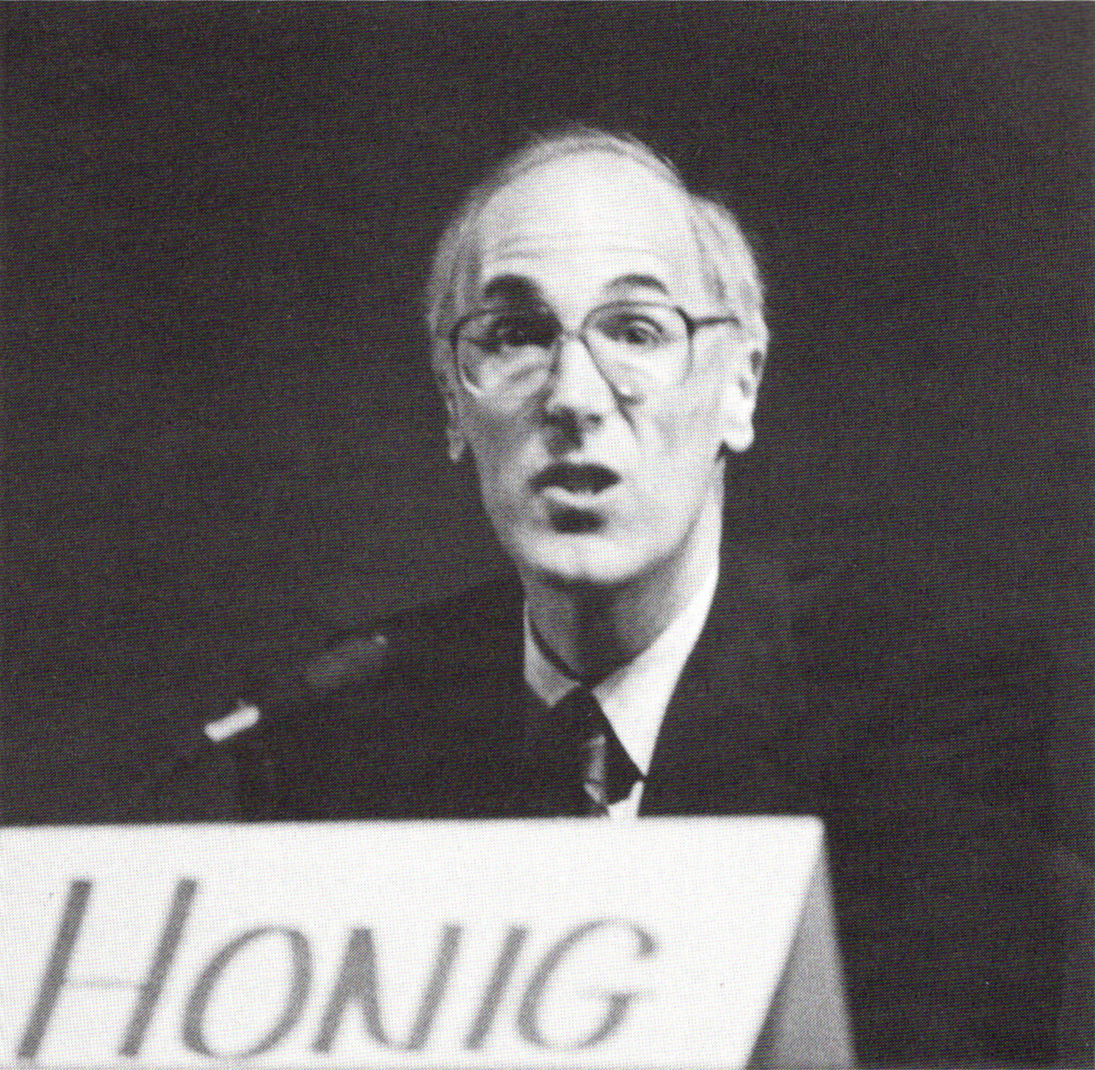 Black and white photo of Bill Honig sitting at a table with a name tag in front of him