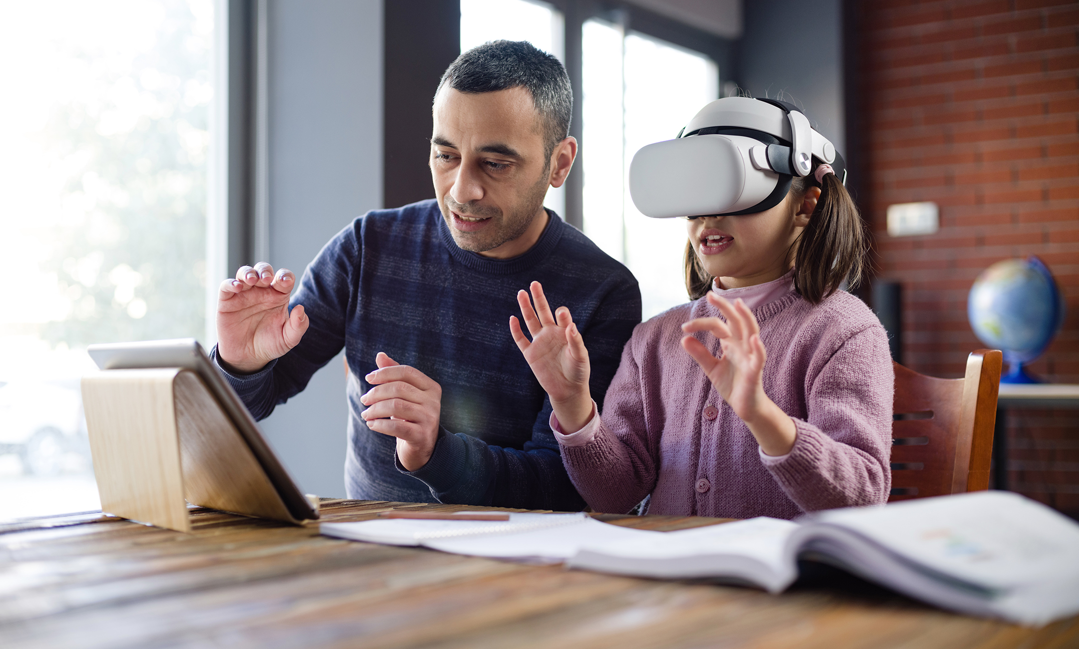 Father helping his daughter, who is wearing a VR headset, with homework