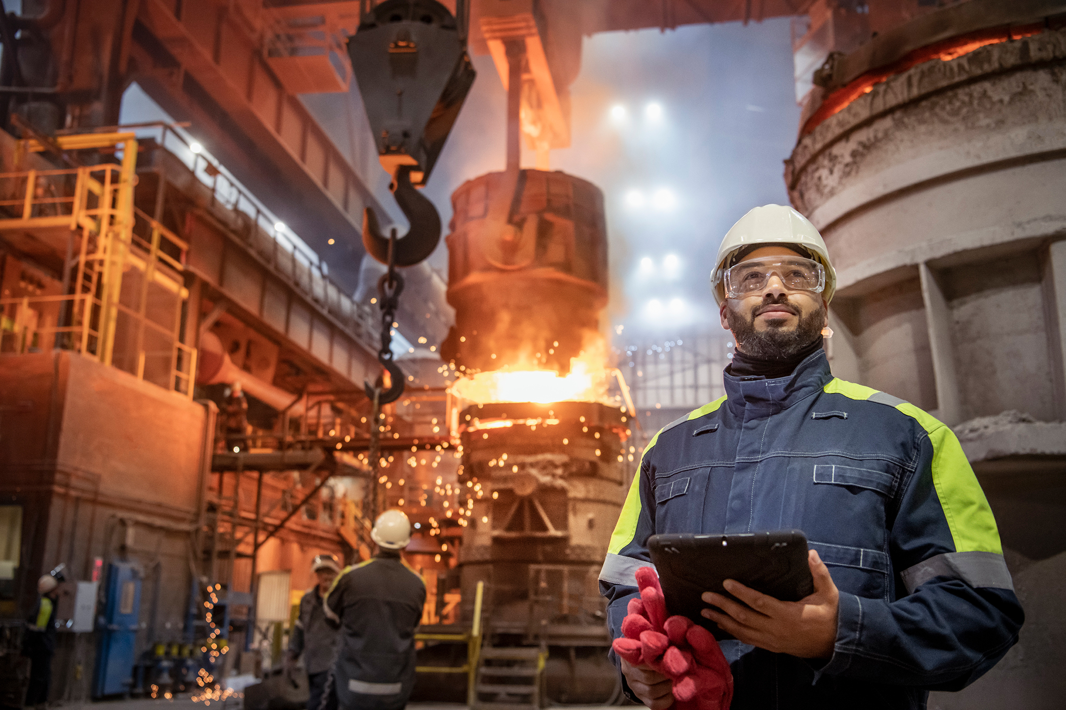 Portrait of steelworker holding a tablet computer during steel pour in steelworks