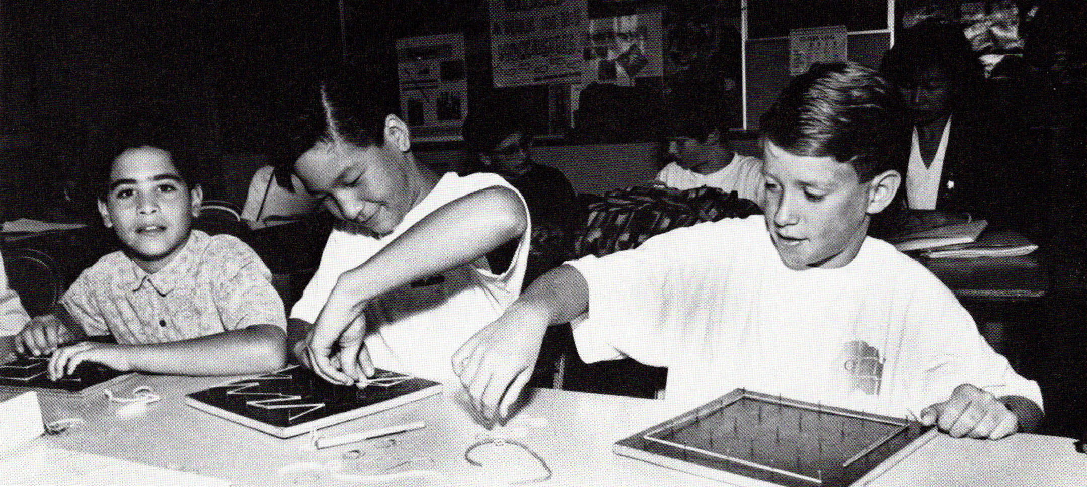 Black and white photo of three male students of different races in a middle school classroom