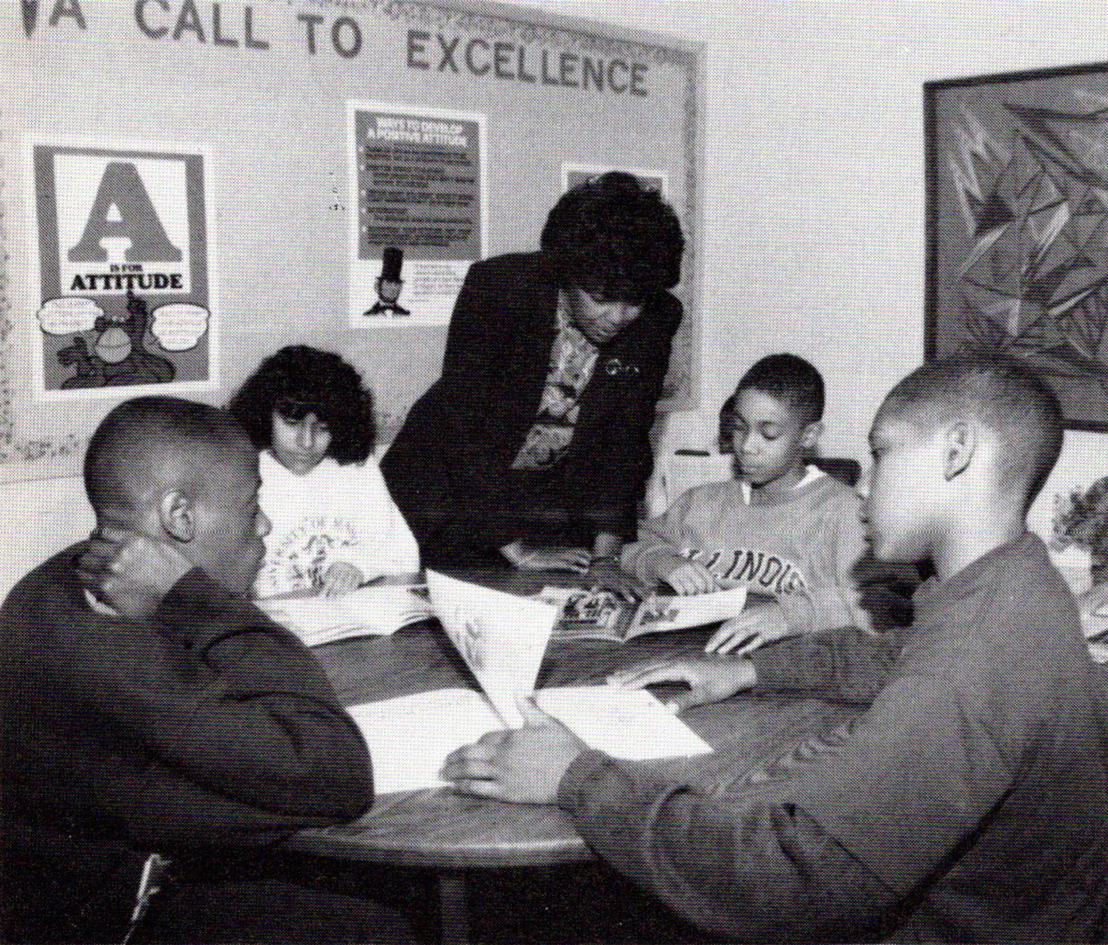 Black and white photo of a teacher helping students reading books in a middle school classroom