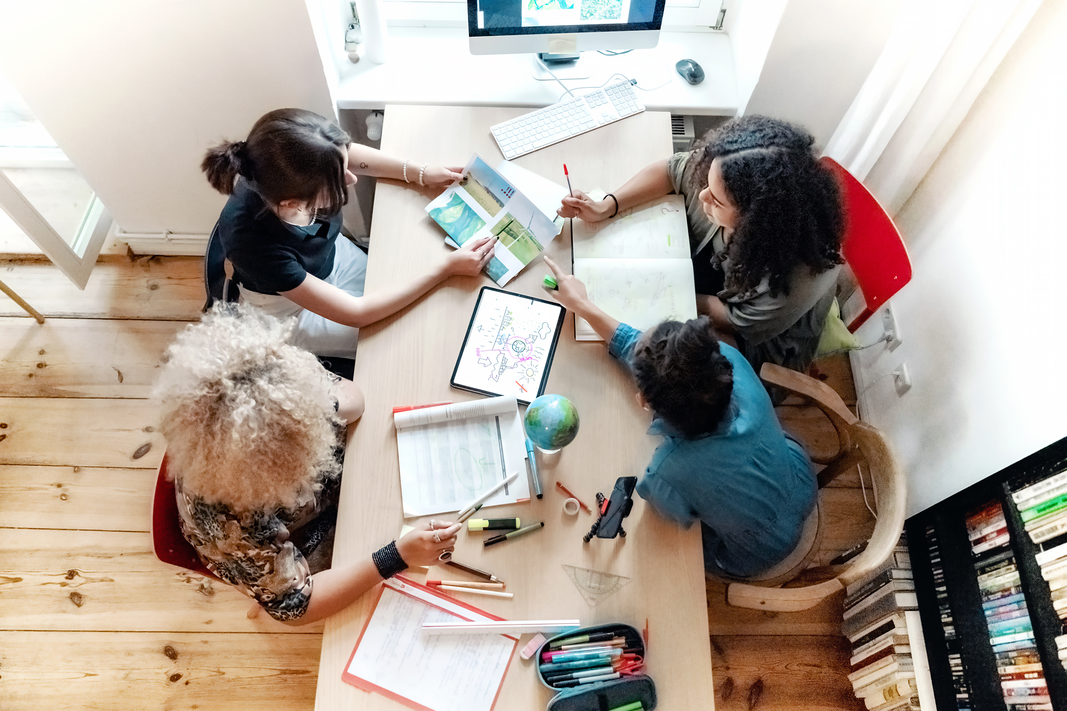 overhead view on four young woman preparing together concepts for climate protection on desk indoors