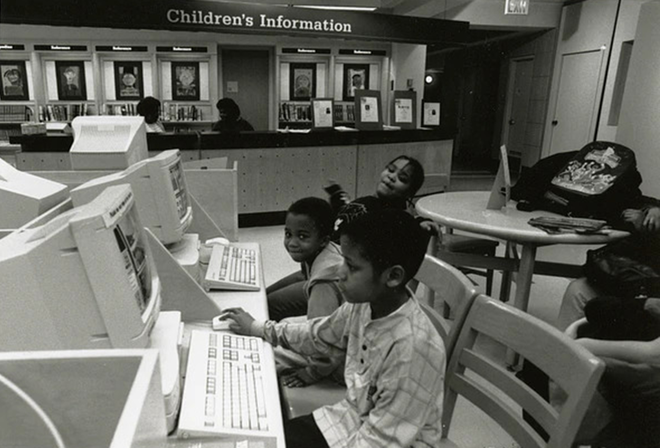 Black and white photo of Three African American children using computers at unknown branch of Brooklyn Public Library