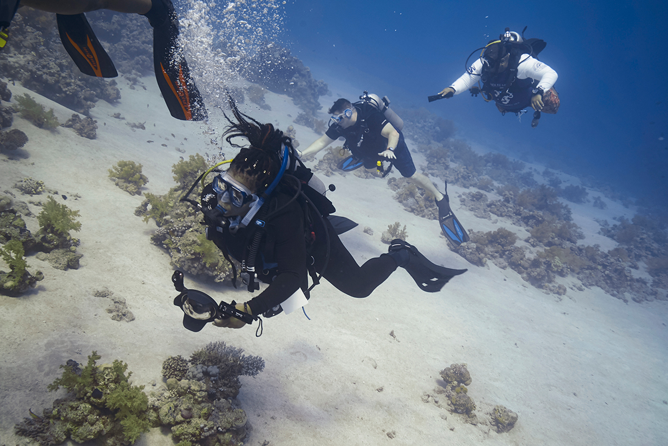Young black woman scuba diving with two men in the background