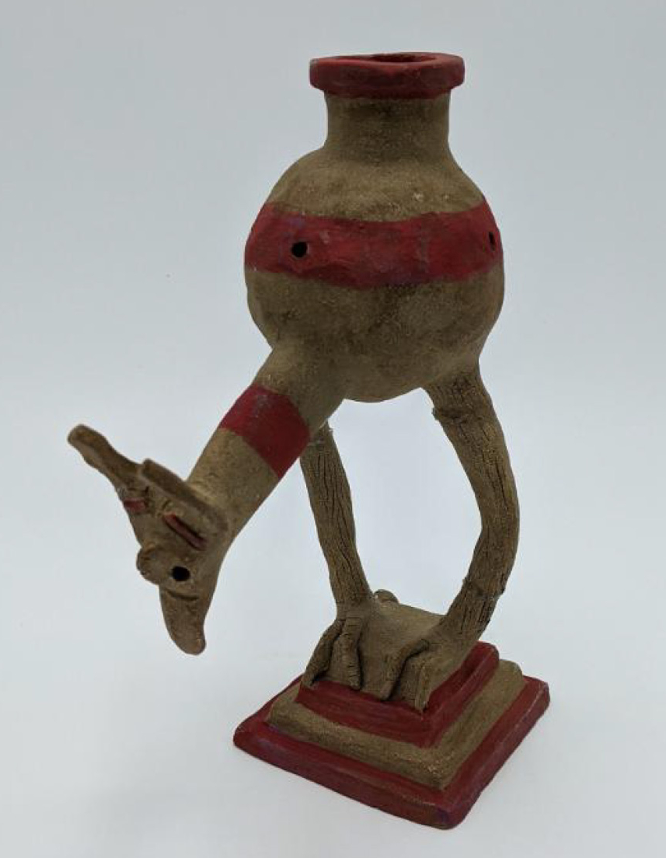 Sculpture of a yellowish creature with a long neck and red stripes in a bowl shape on long legs