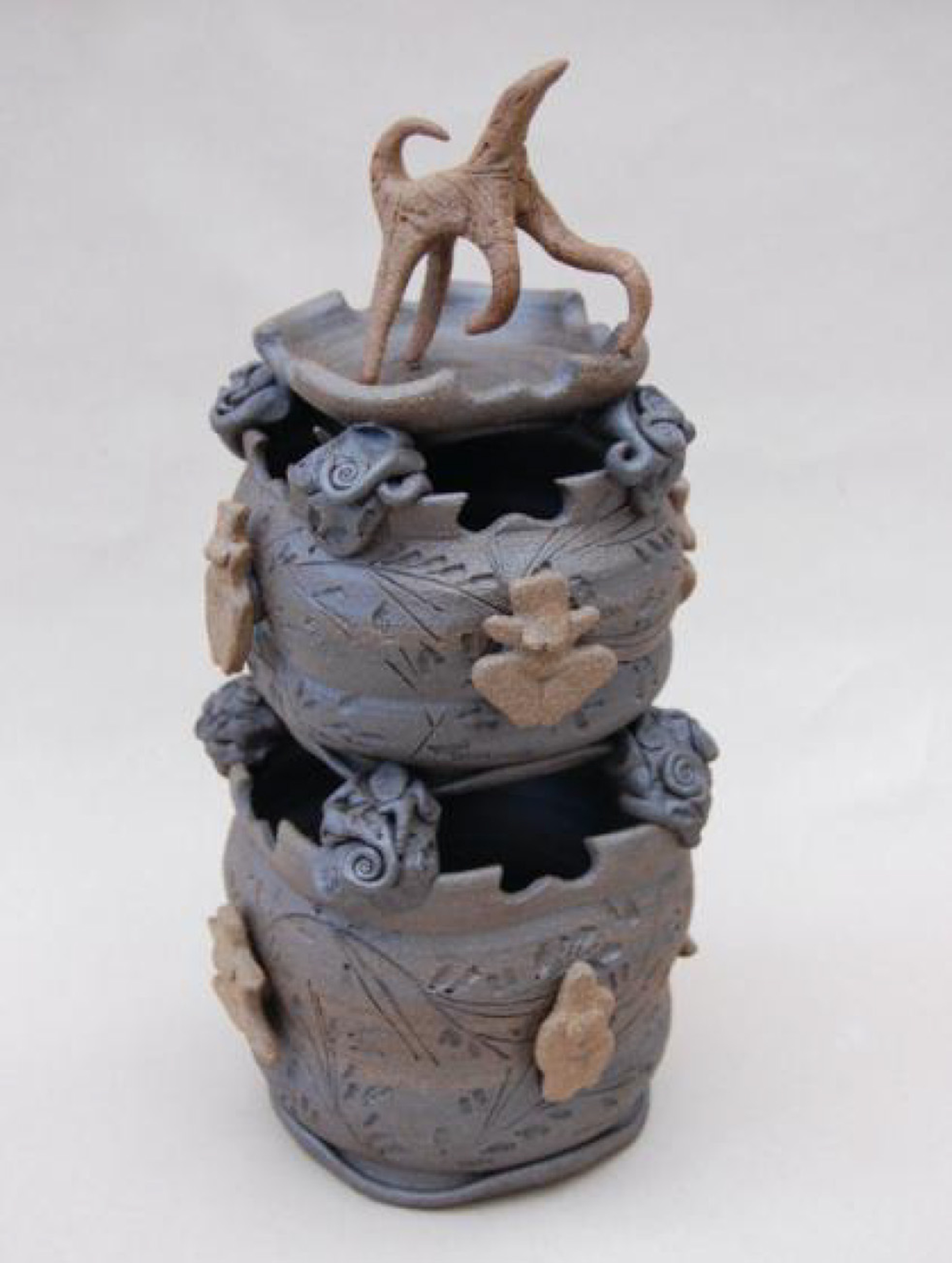 Sculpture shaped like two blue cups stacked on top of each other with animal-like figure at the top