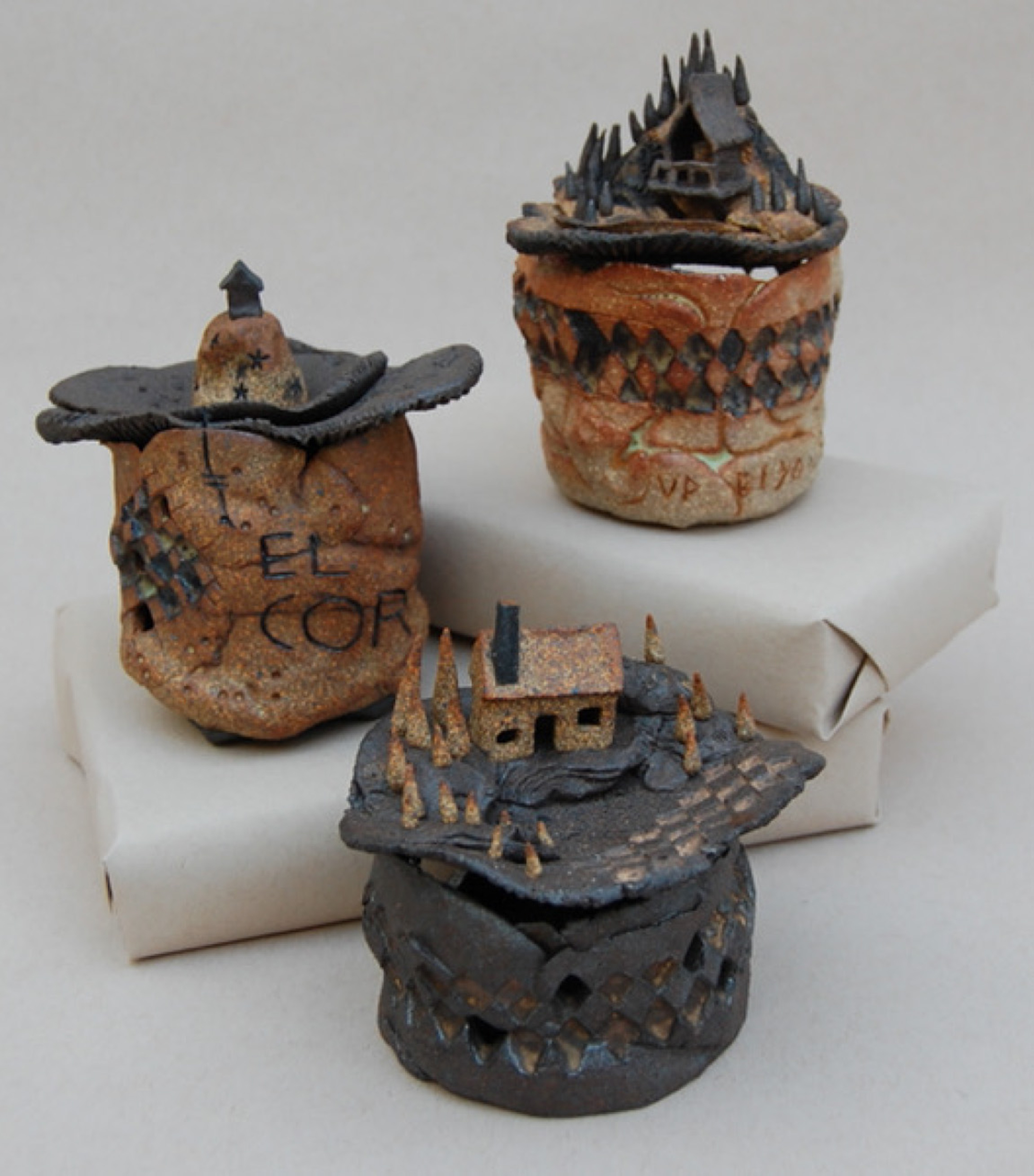 Three cup-shaped sculptures with little houses on top of each