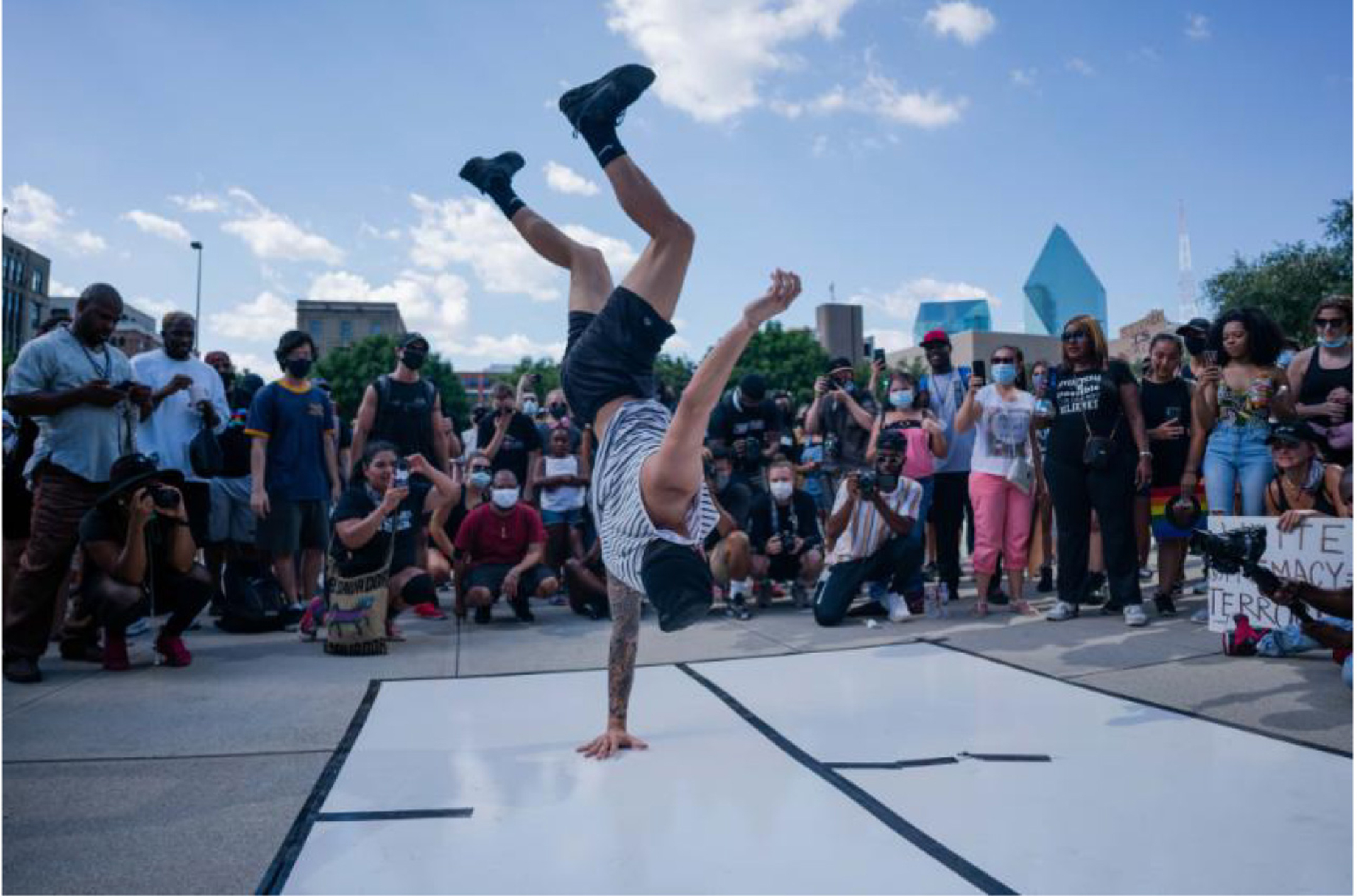 Color photograph of a white man breakdancing for a crowd