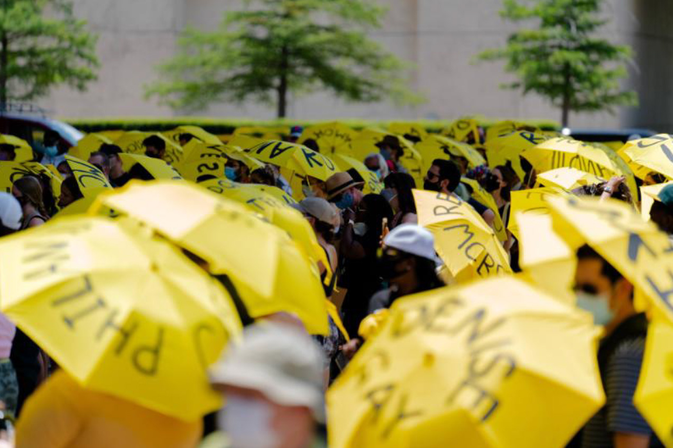 Color photograph of a crowd of protesters with yellow umbrellas