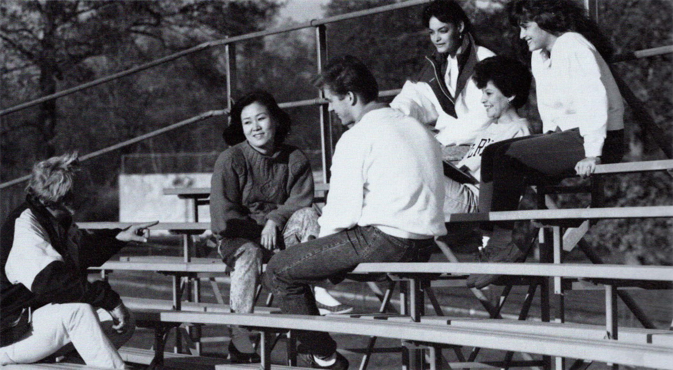 Black and white photo of six community college students sitting on bleachers