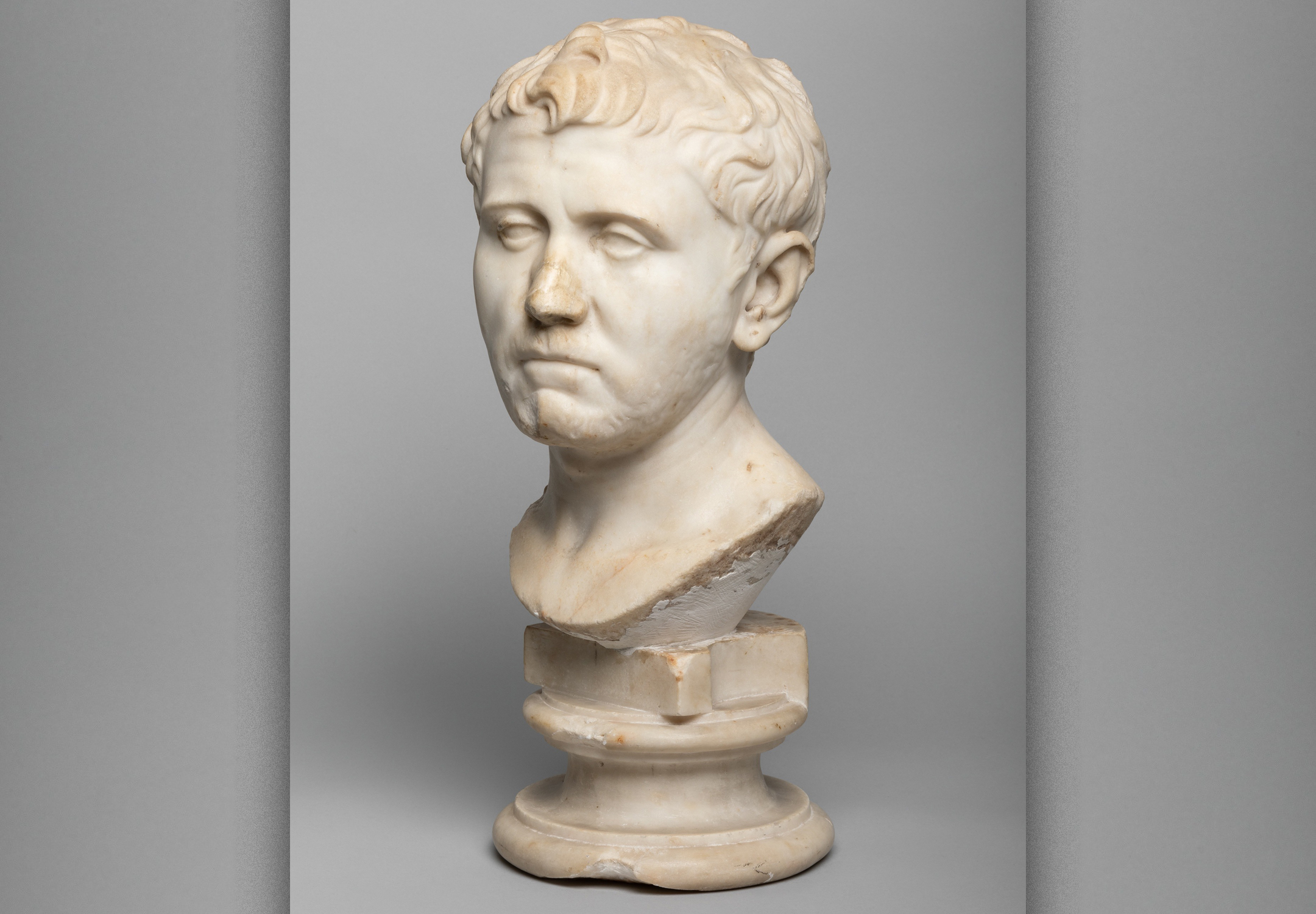 Photo of a marble bust of a man against a gray background