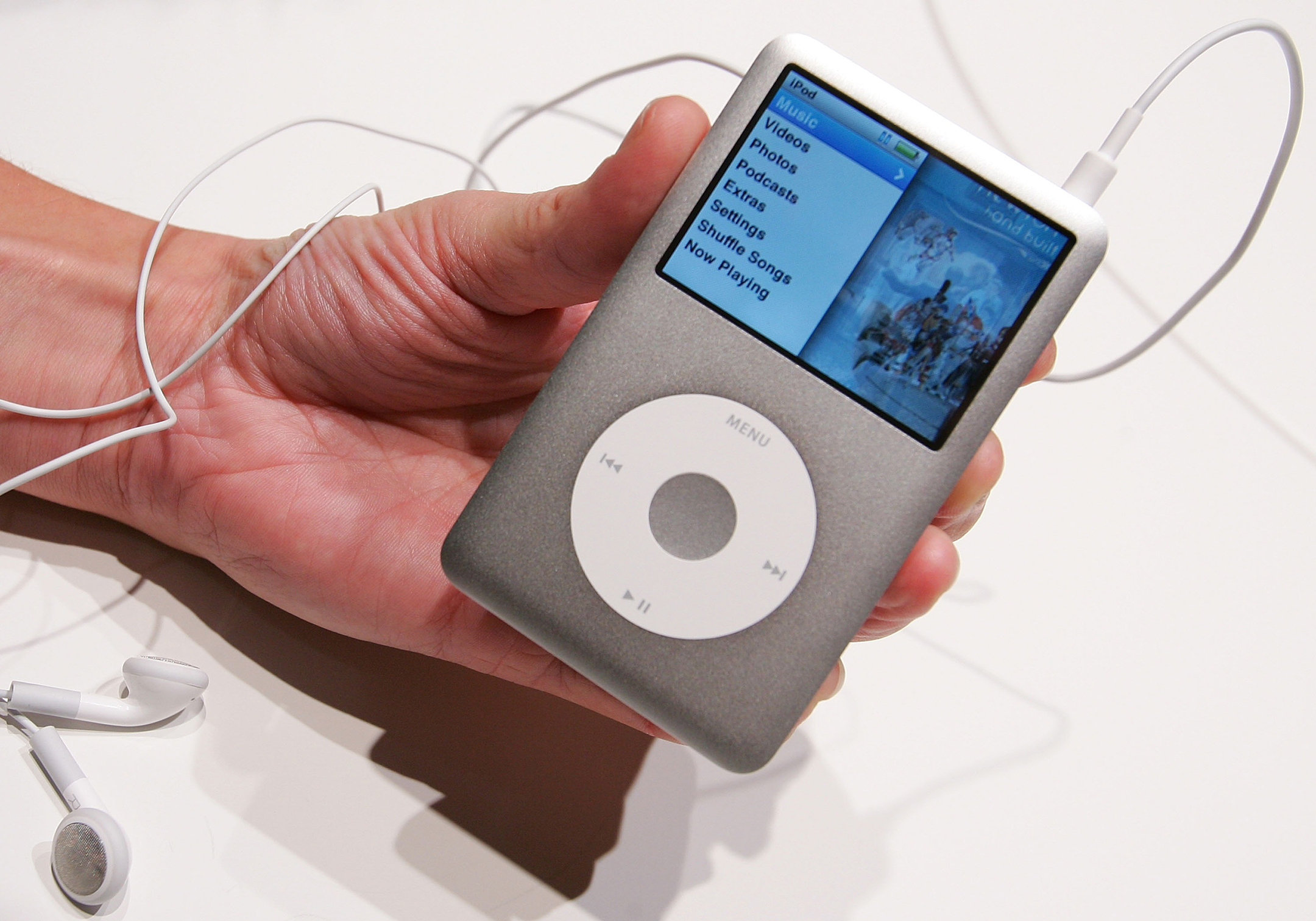 Hand holding an iPod with earphone cable attached