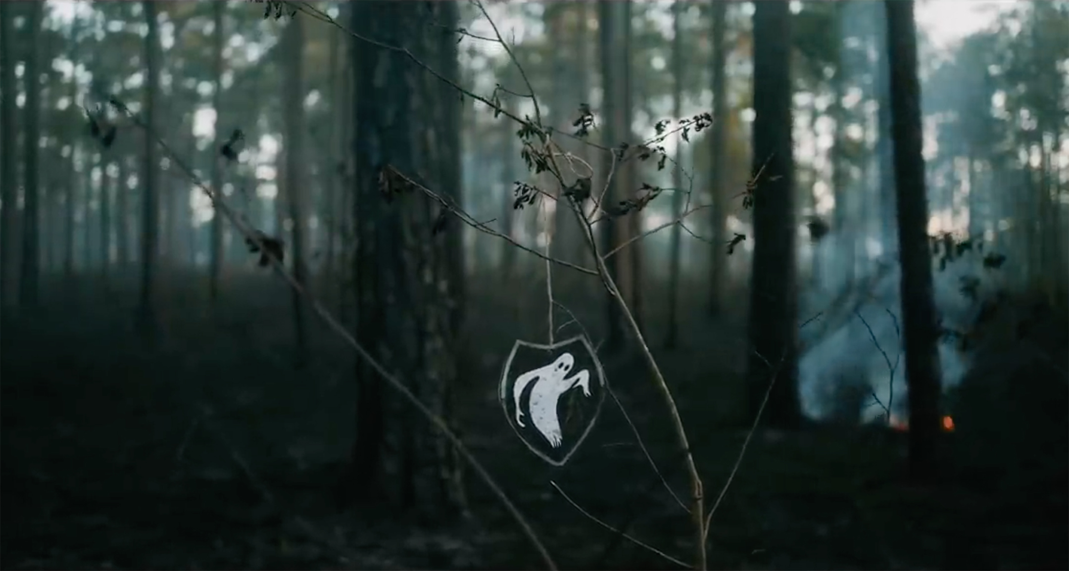 Screenshot from a video showing a ghost keychain hanging on a branch in a barren forest