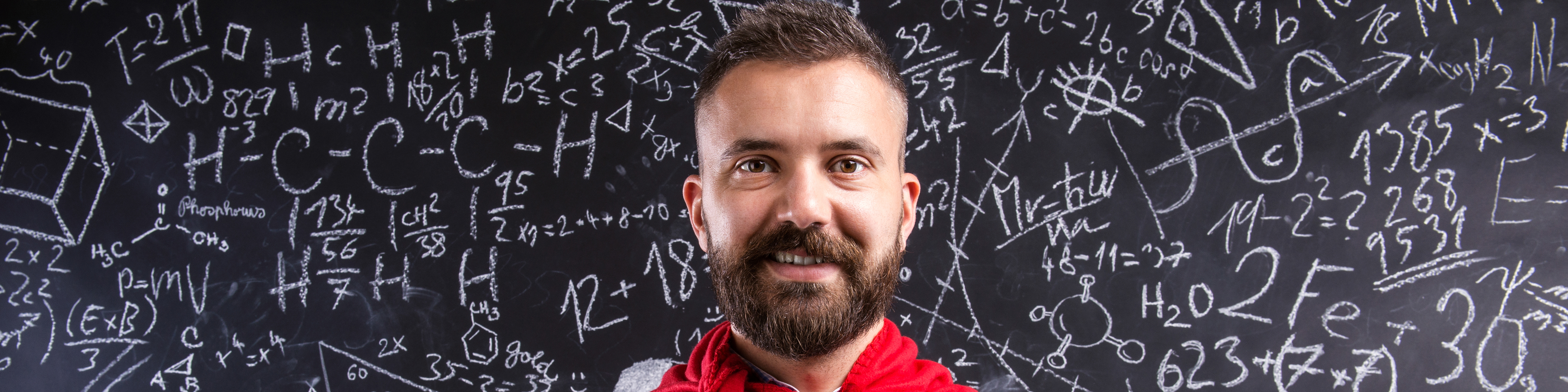 teacher in red cape standing against big blackboard with mathematical symbols and formulas