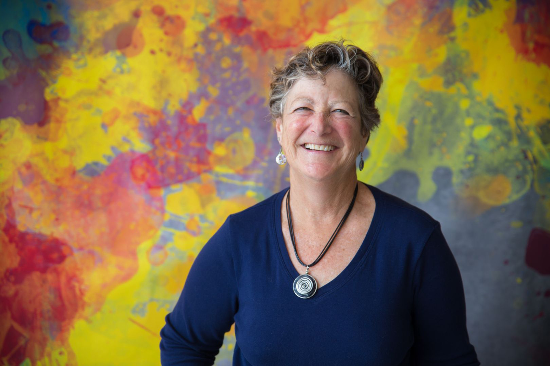woman smiling at the camera against a colorful background painting