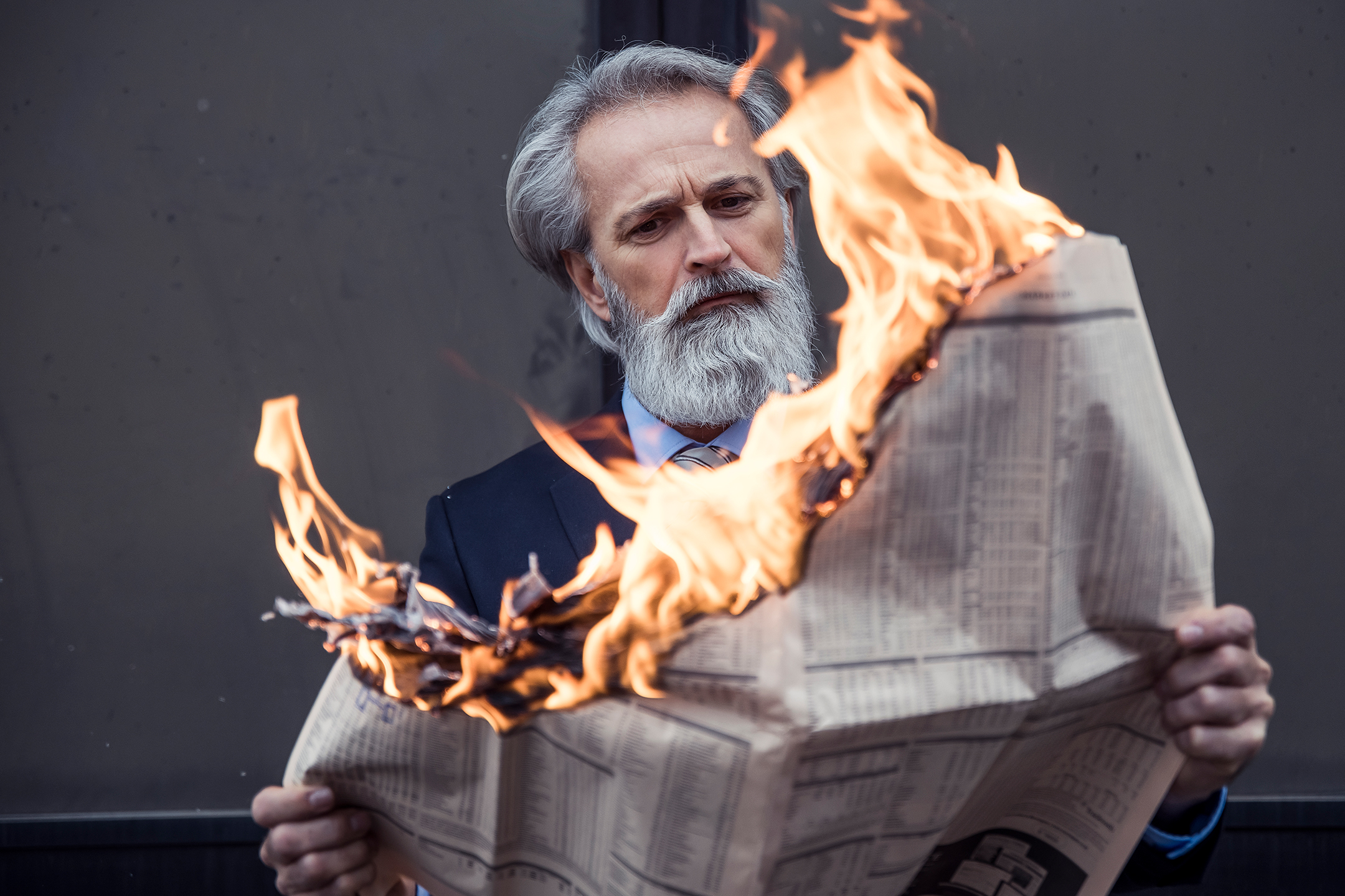 Handsome well dressed businessman reading burning newspaper