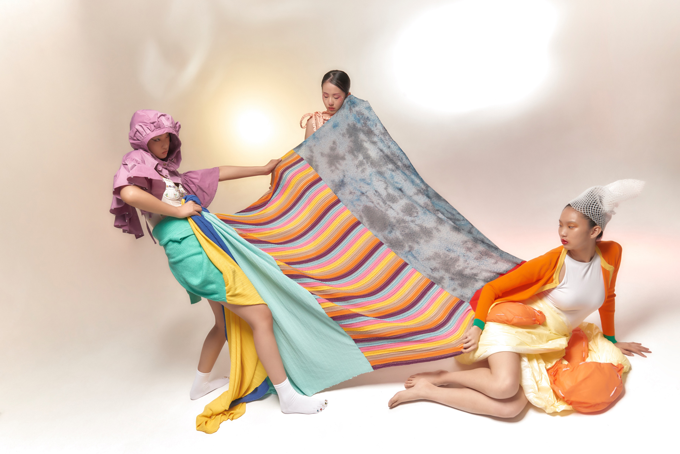 Photograph of three young women pulling at a large blanket