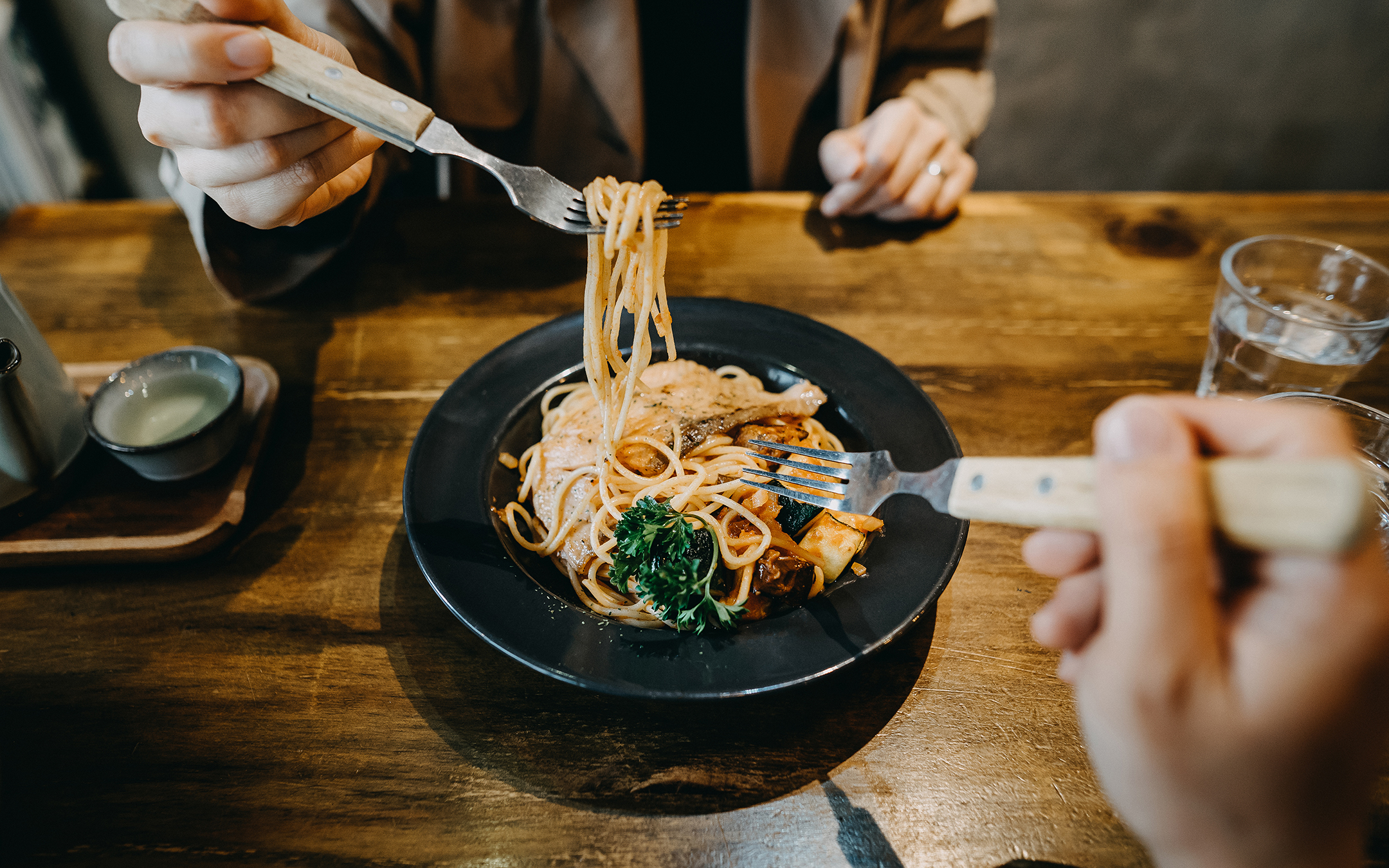 Hands of couple sharing and enjoying freshly made pasta in a restaurant