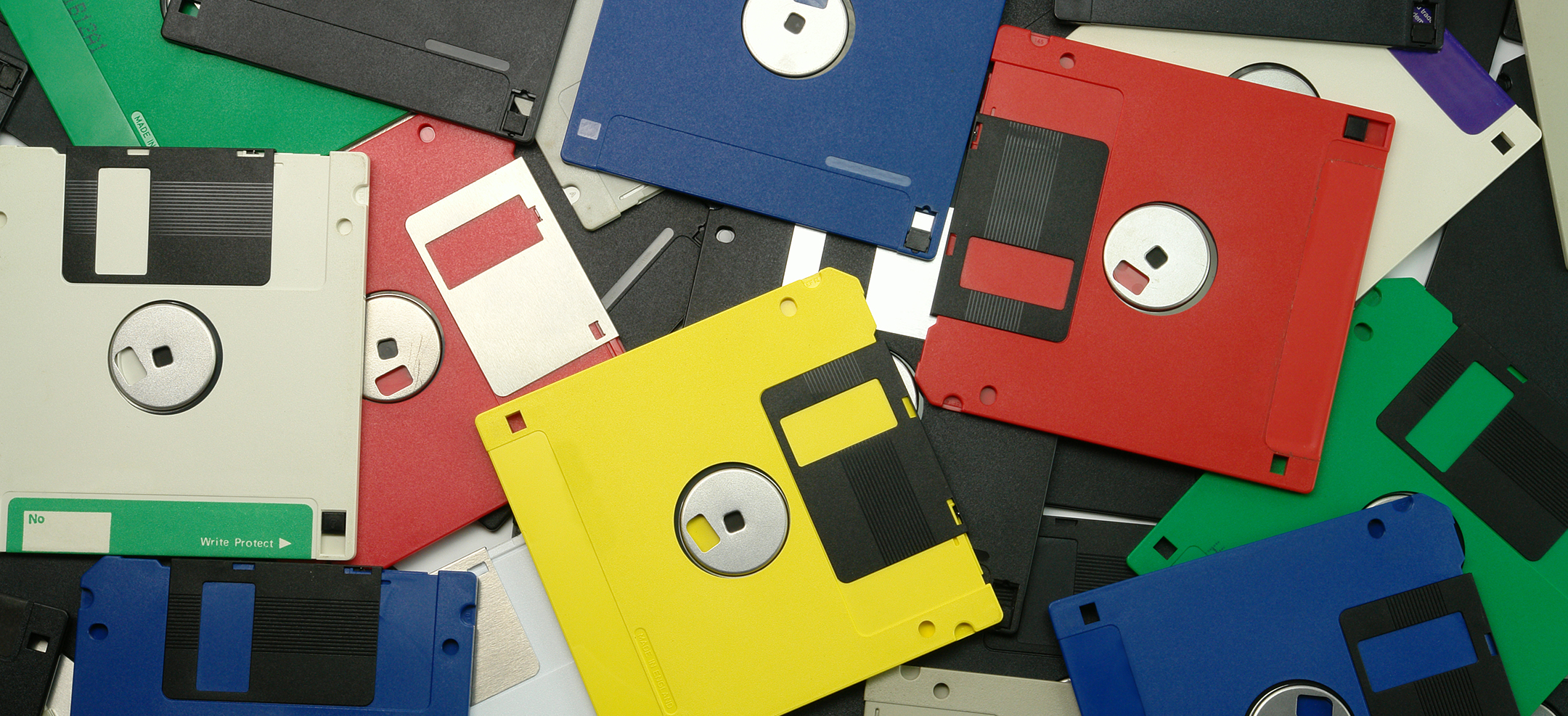 vintage floppy 3.5-inch disks in various colors spread out on a table, top view