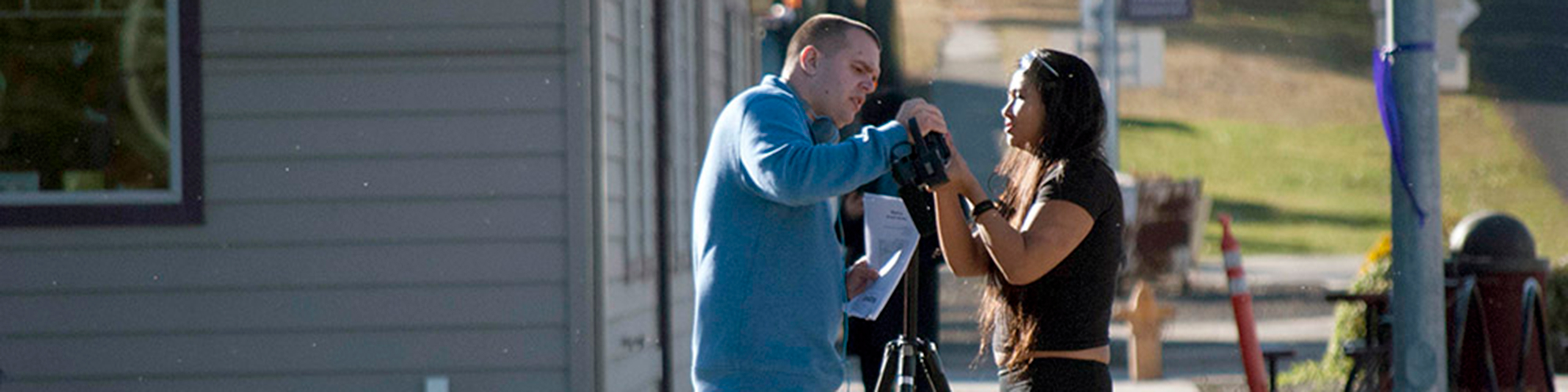 Two student journalists set up a camera on a street