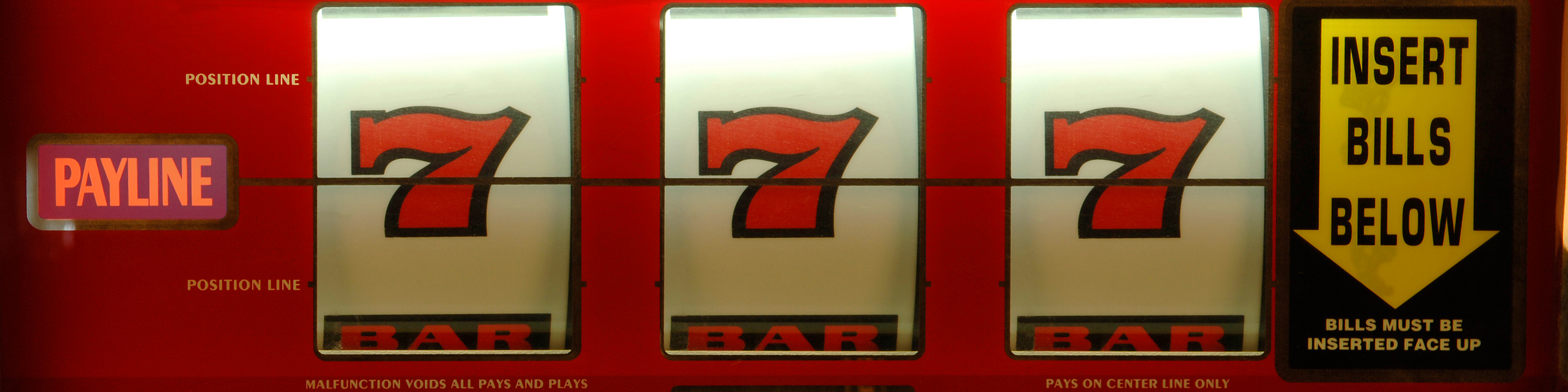 Close up of a red slot machine with straight sevens