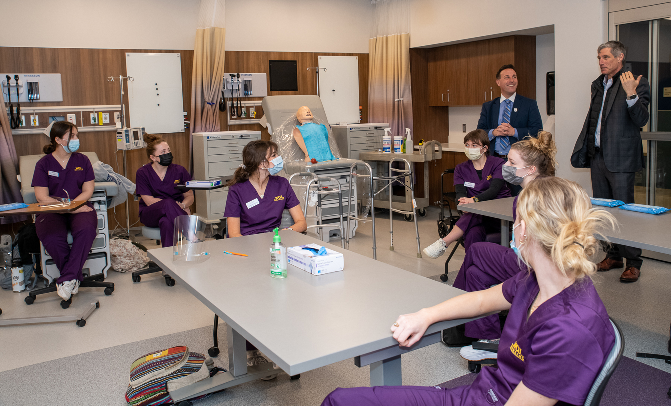 Dan Greenstein speaking to a lab full of nursing students in purple medical scrubs
