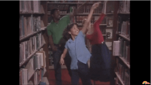 Animated gif of three people pumping their arms and running through library stacks