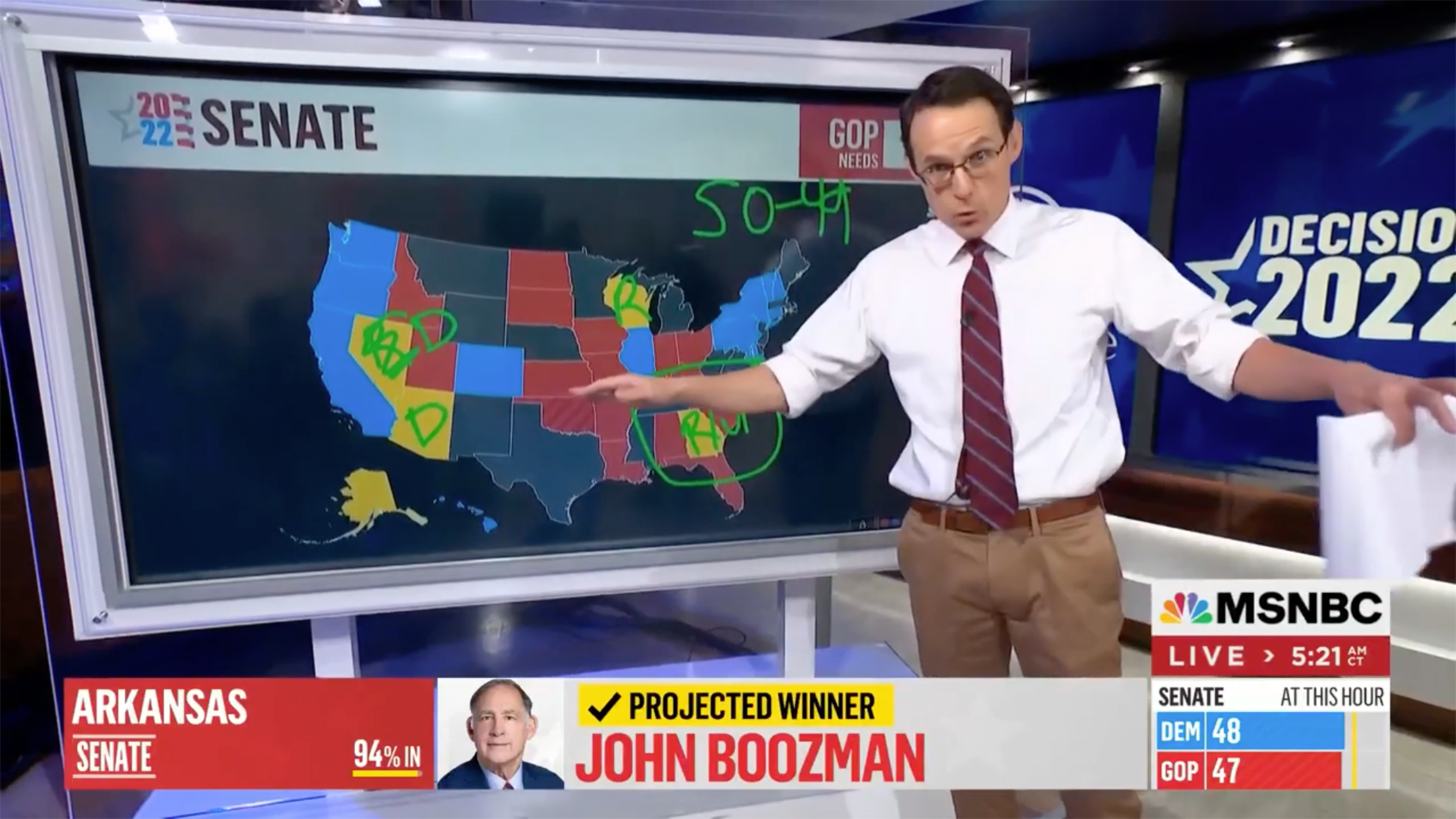 Screenshot of a video of a man in a white shirt and tie gesturing in front of a video screen displaying a map of the United States with the states represented in different colors