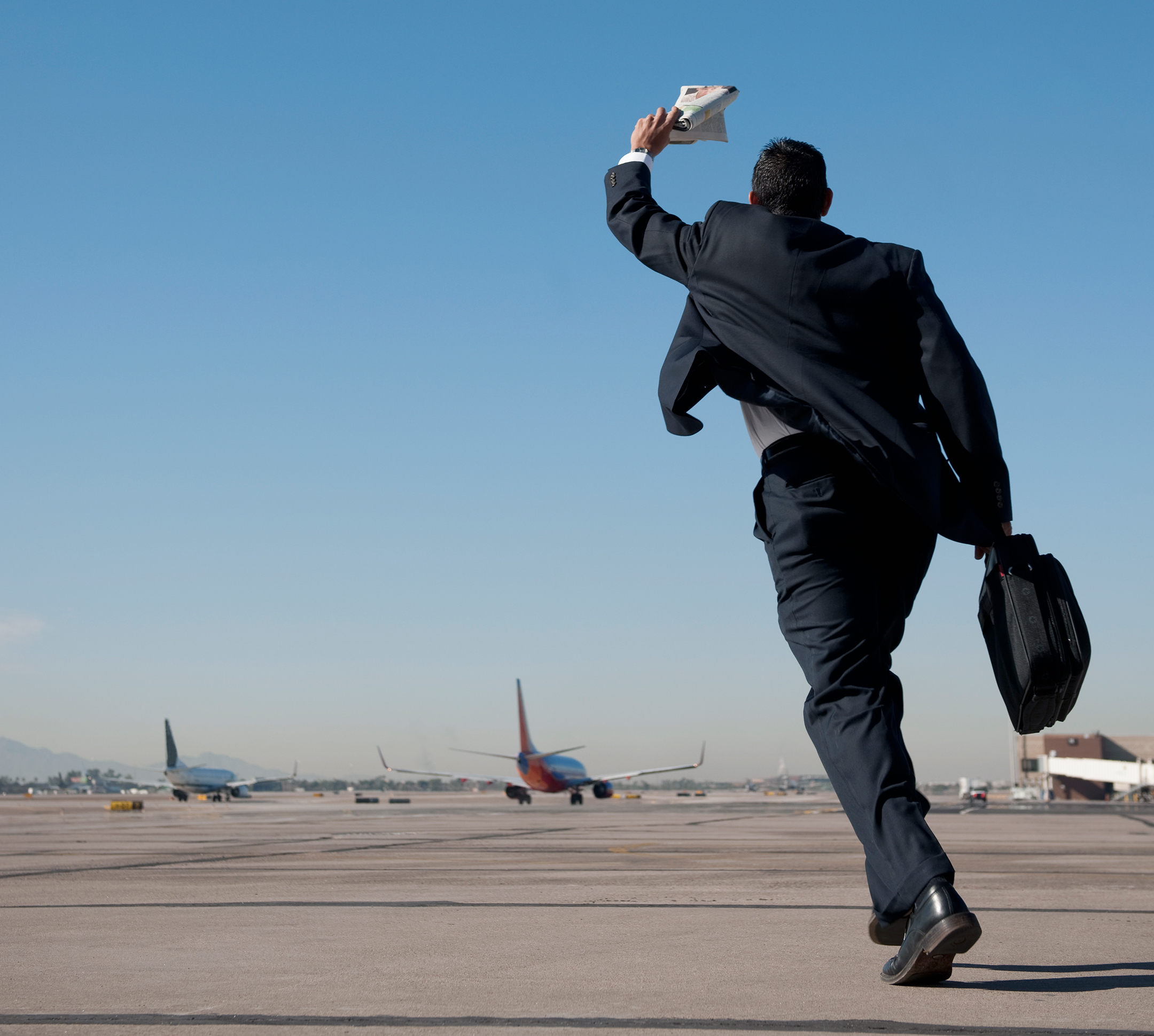 Businessman running on airport tarmac chasing after a plane