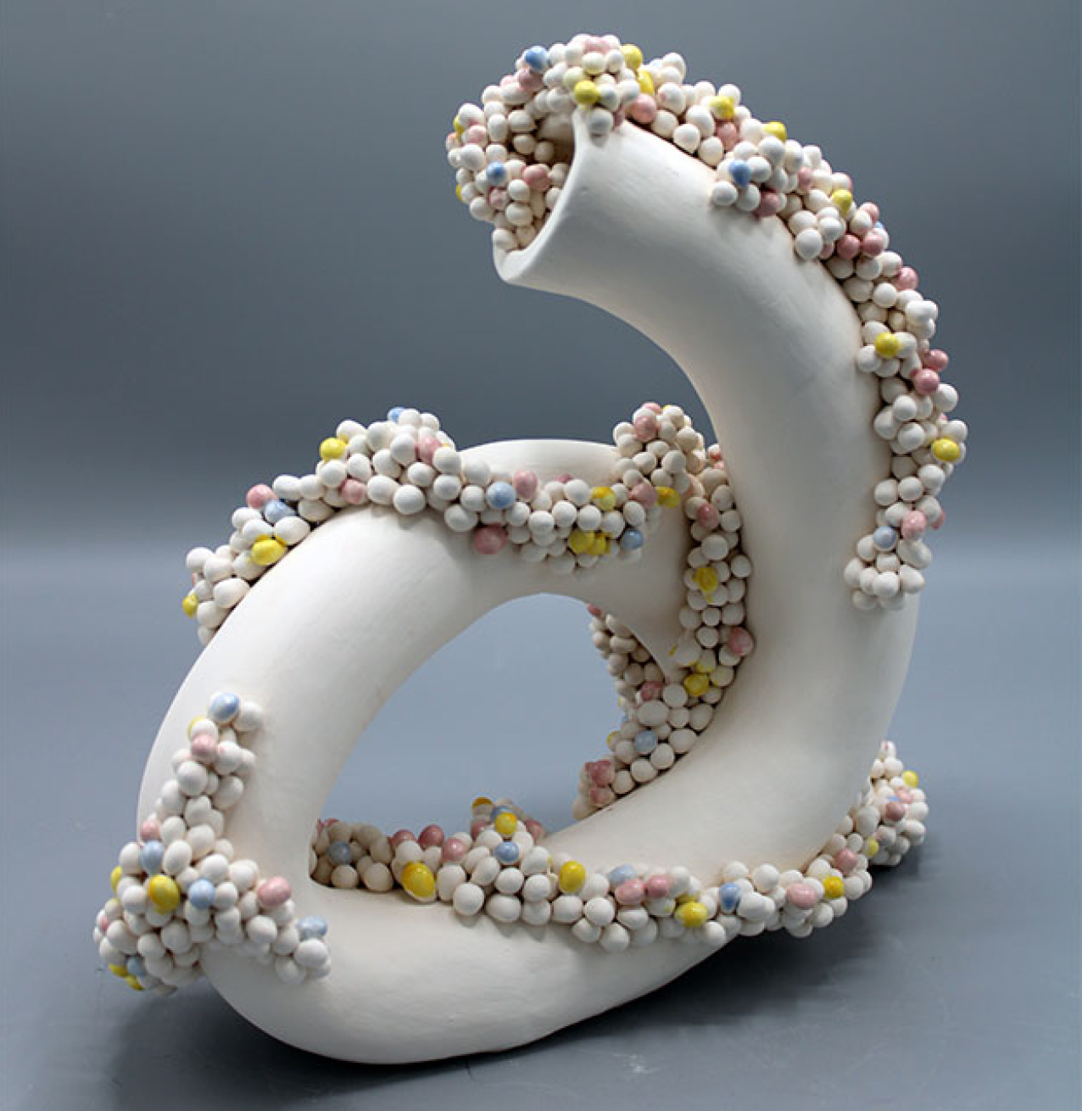 white tubular sculpture with small pastel colored spheres running up it