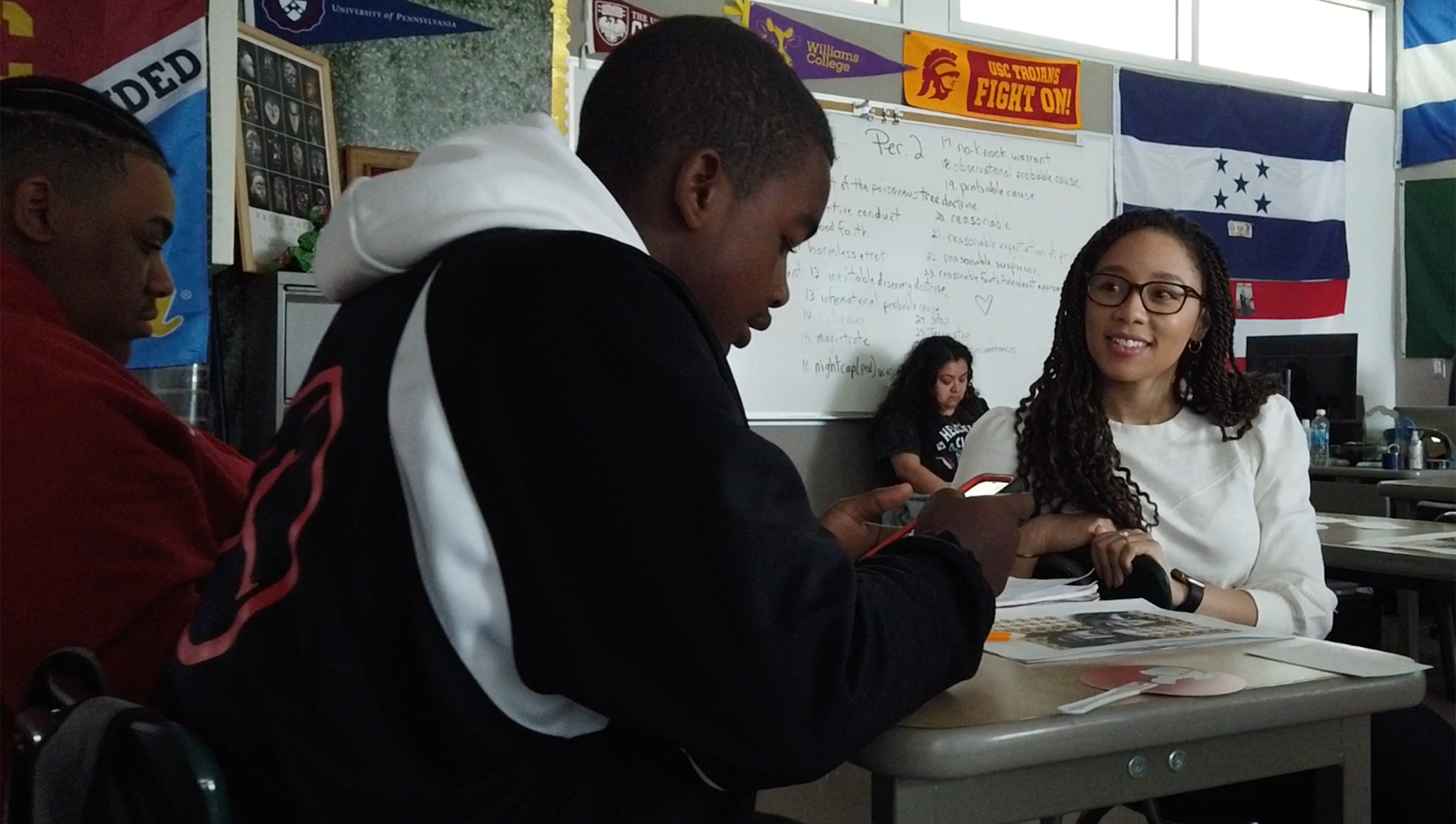 Brandi Waters sits at a school desk and speaks with two young black male students