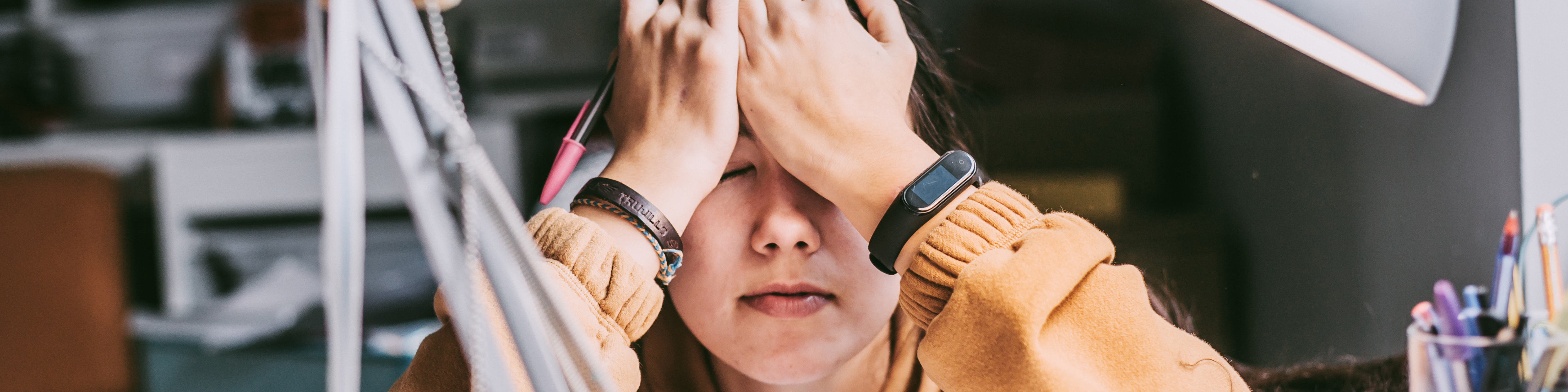 a frustrated student sitting at a desk covering her eyes