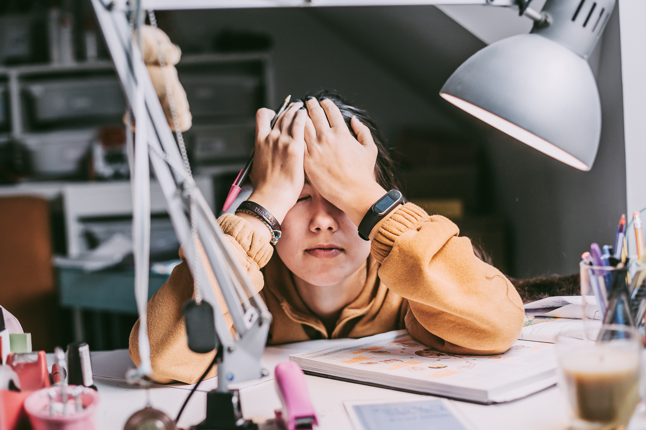 a frustrated student sitting at a desk covering her eyes