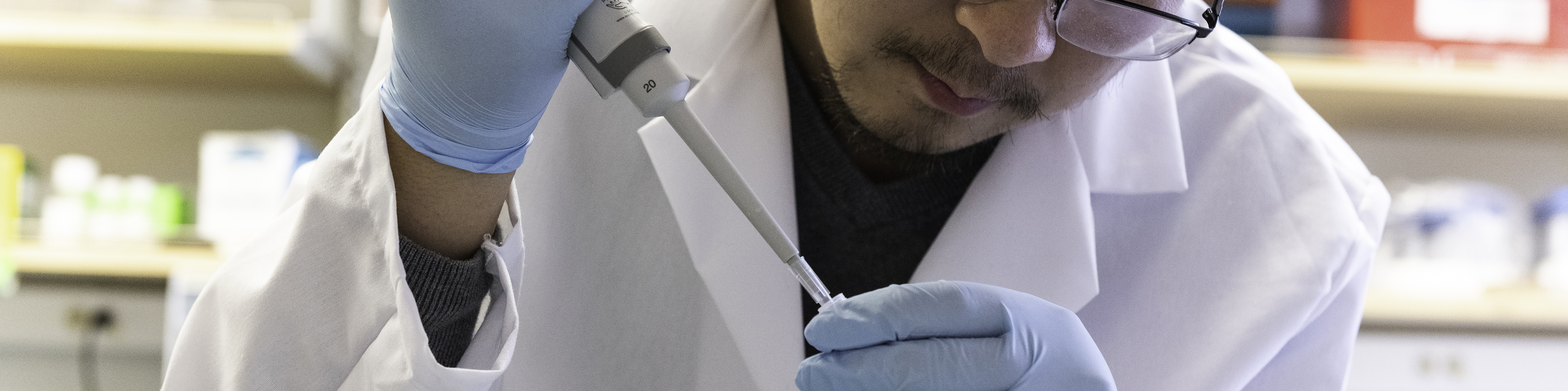 a research associate at the university of texas holds a syringe in one hand and a test tube in another while working on researching coronavirus treatment