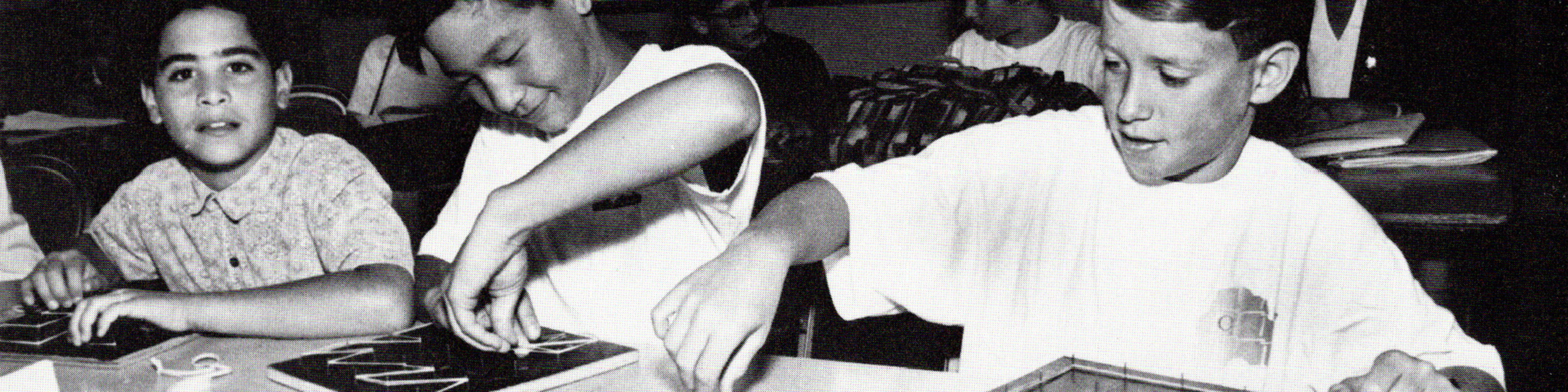 Black and white photo of three male students of different races in a middle school classroom