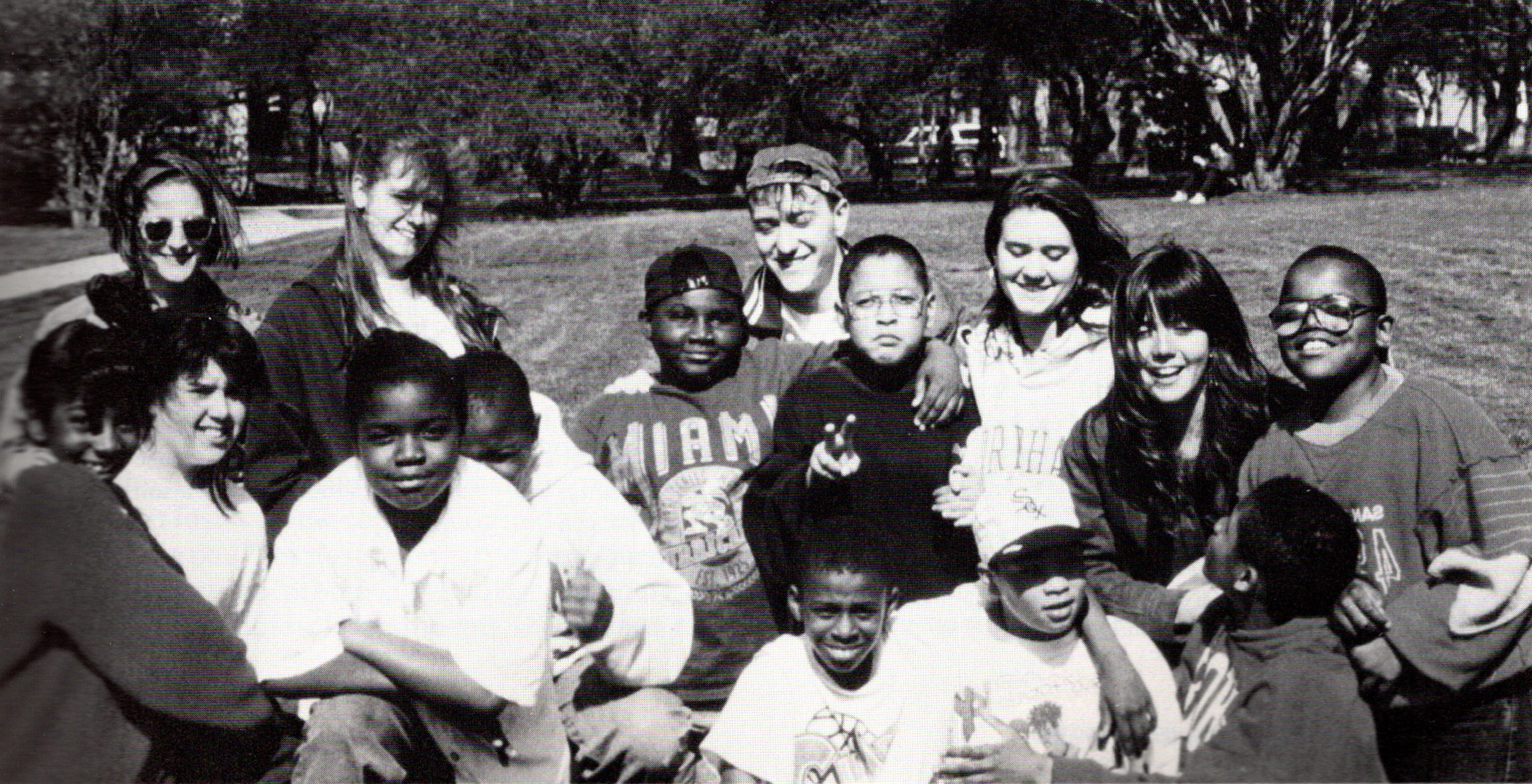 Black and white photo of a group of students and teachers smiling for the camera on a college campus
