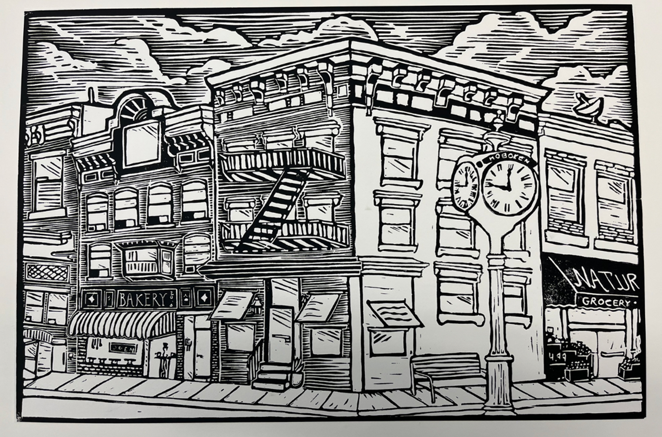 Black and white wood block print of a street corner depicting low-rise buildings and a clock